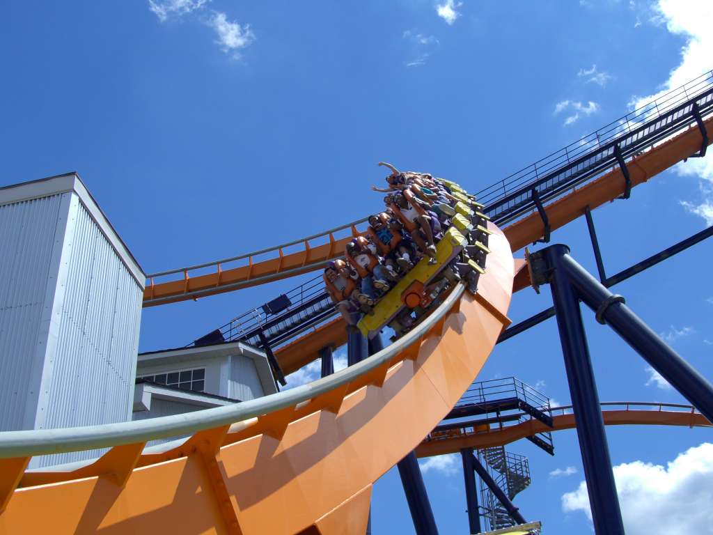 A Dominator train snaking around the station at Kings Dominion, riders' legs dangling from the floorless train