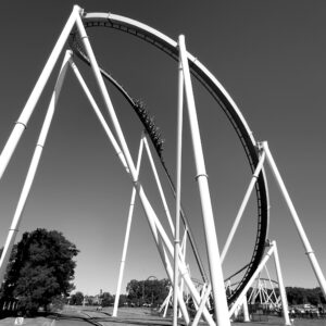 A Fury 325 train sweeping through the drop curve under the white supports, black and white, Carowinds, October 2024