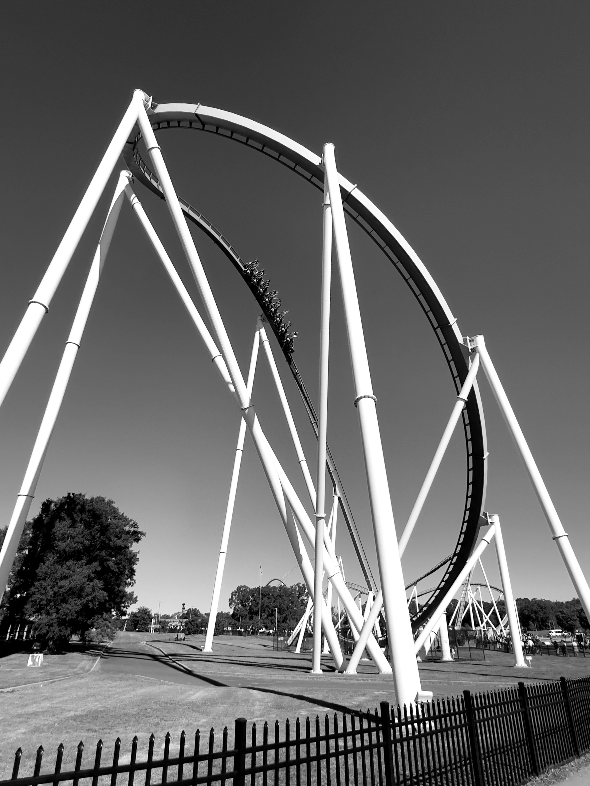 A Fury 325 train sweeping through the drop curve under the white supports, black and white, Carowinds, October 2024