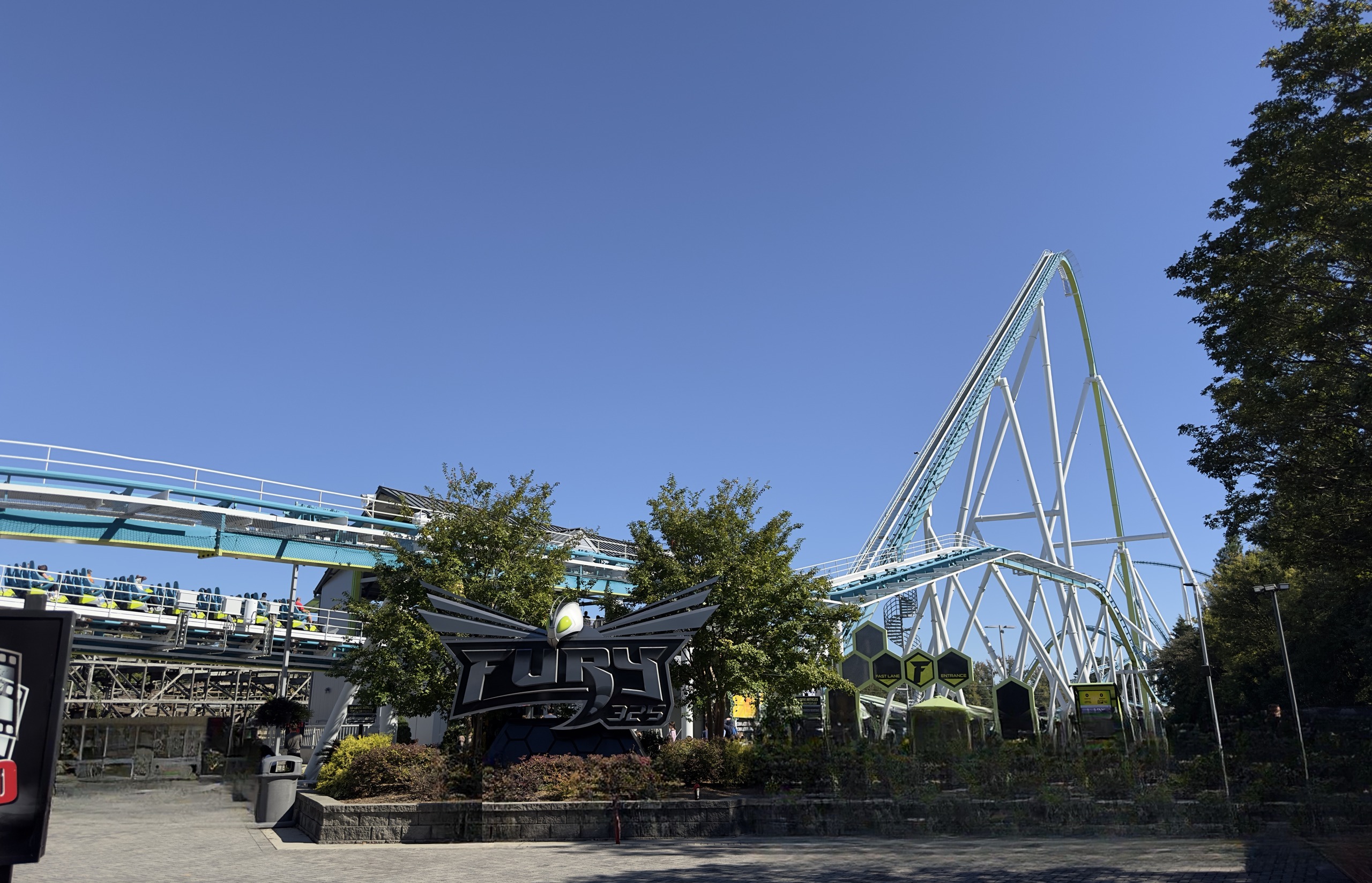 The Fury 325 entrance plaza with its winged sign and the lift hill rising behind it, Carowinds, October 2024
