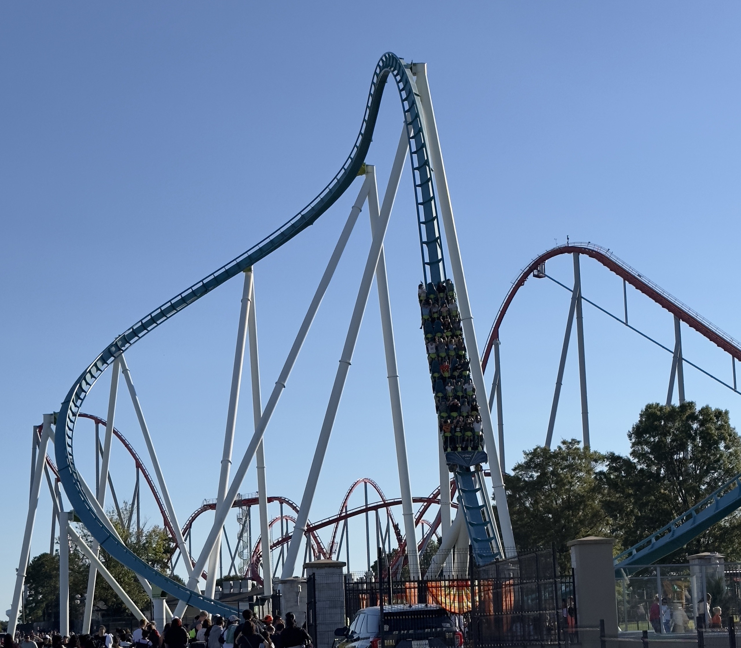 A Fury 325 train diving down the 81-degree drop beside Thunder Striker's red hills, Carowinds, October 2024