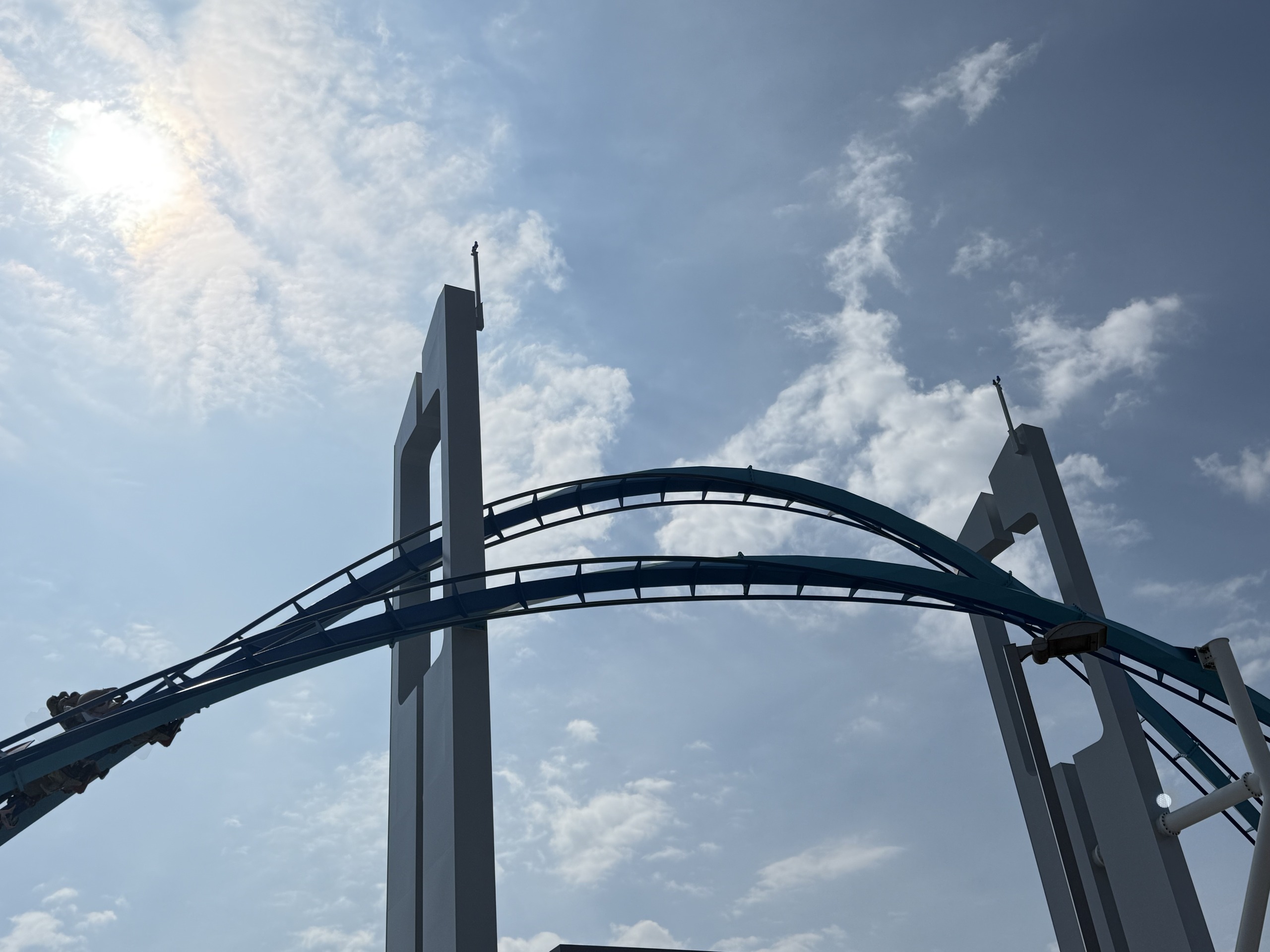 GateKeeper's keyhole towers and teal track silhouetted against the sun, with a train entering at the left