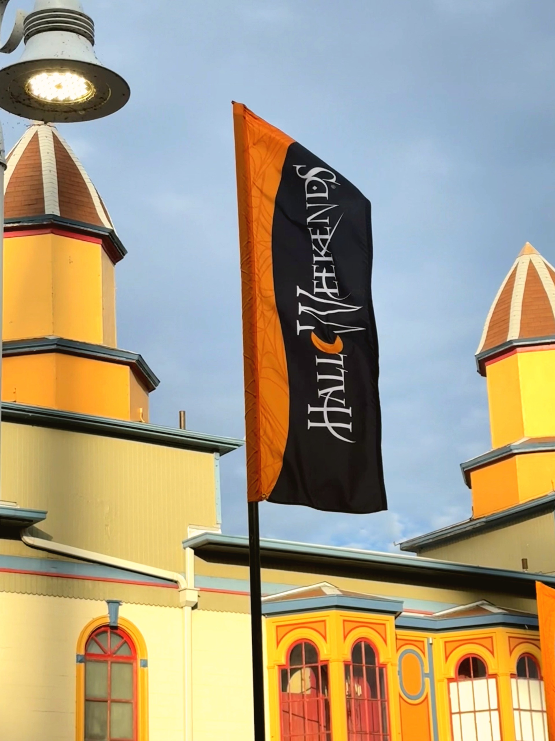 A black and orange HalloWeekends banner in front of the ornate yellow Grand Pavilion cupolas