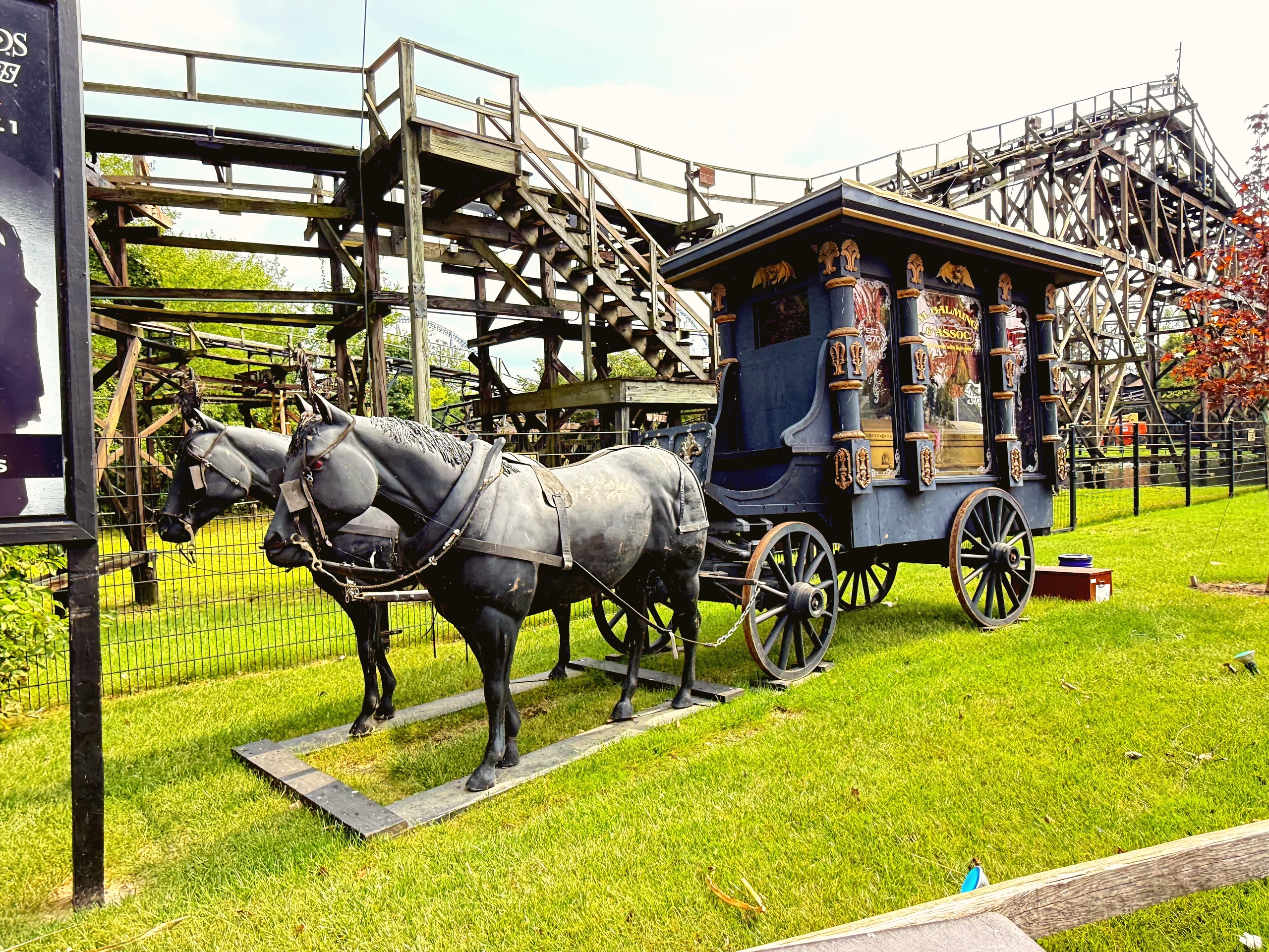 Bronze horse statues pulling an antique hearse in front of Cedar Creek Mine Ride's wooden structure