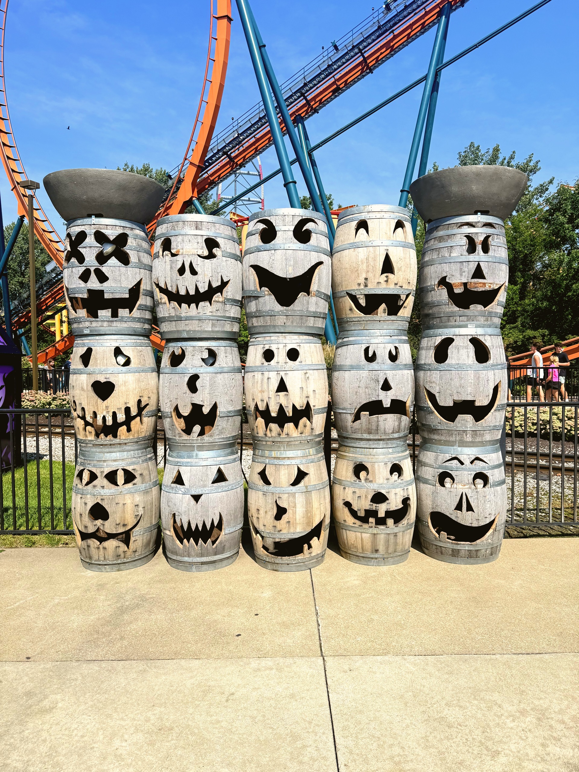 Stacks of carved jack-o-lantern barrels with Iron Dragon's orange track and teal supports behind
