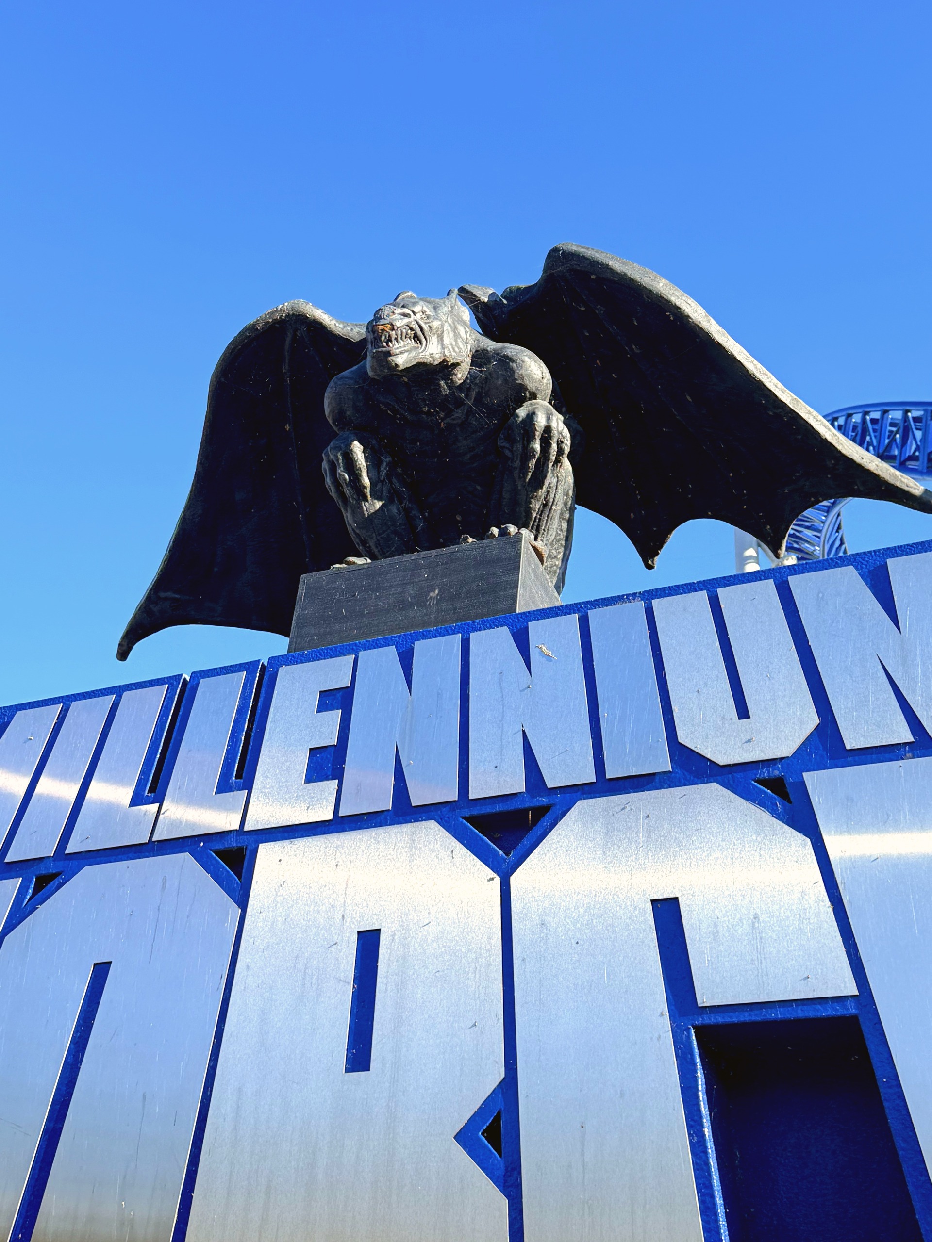 The winged gargoyle statue atop the Millennium Force entrance sign against a blue sky