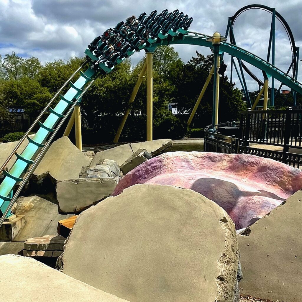 A Kraken train cresting the hill above the splash rocks as the teal track drops toward the tunnel, SeaWorld Orlando, March 2021