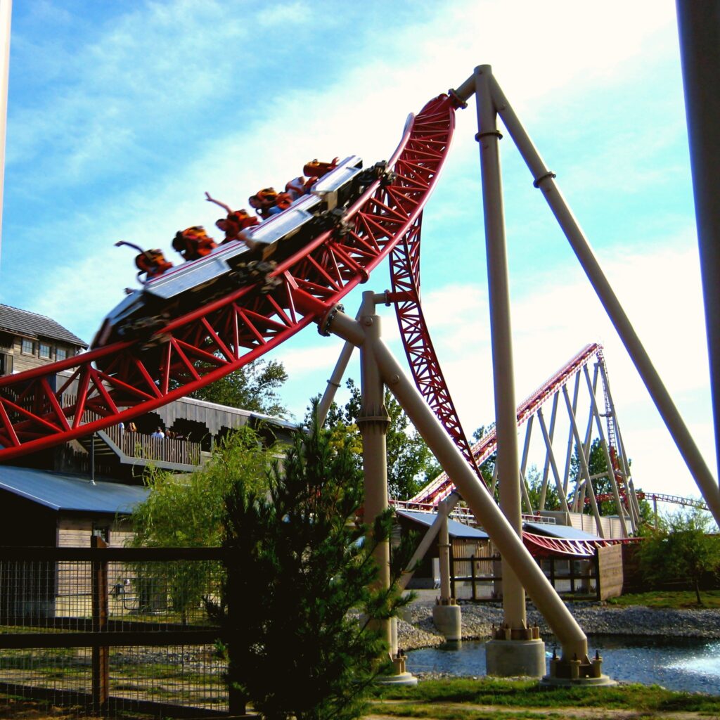 A Maverick train cresting a hill beside the station at Cedar Point, riders' hands up