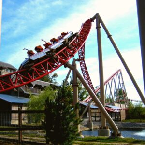 A Maverick train cresting a hill beside the station at Cedar Point, riders' hands up