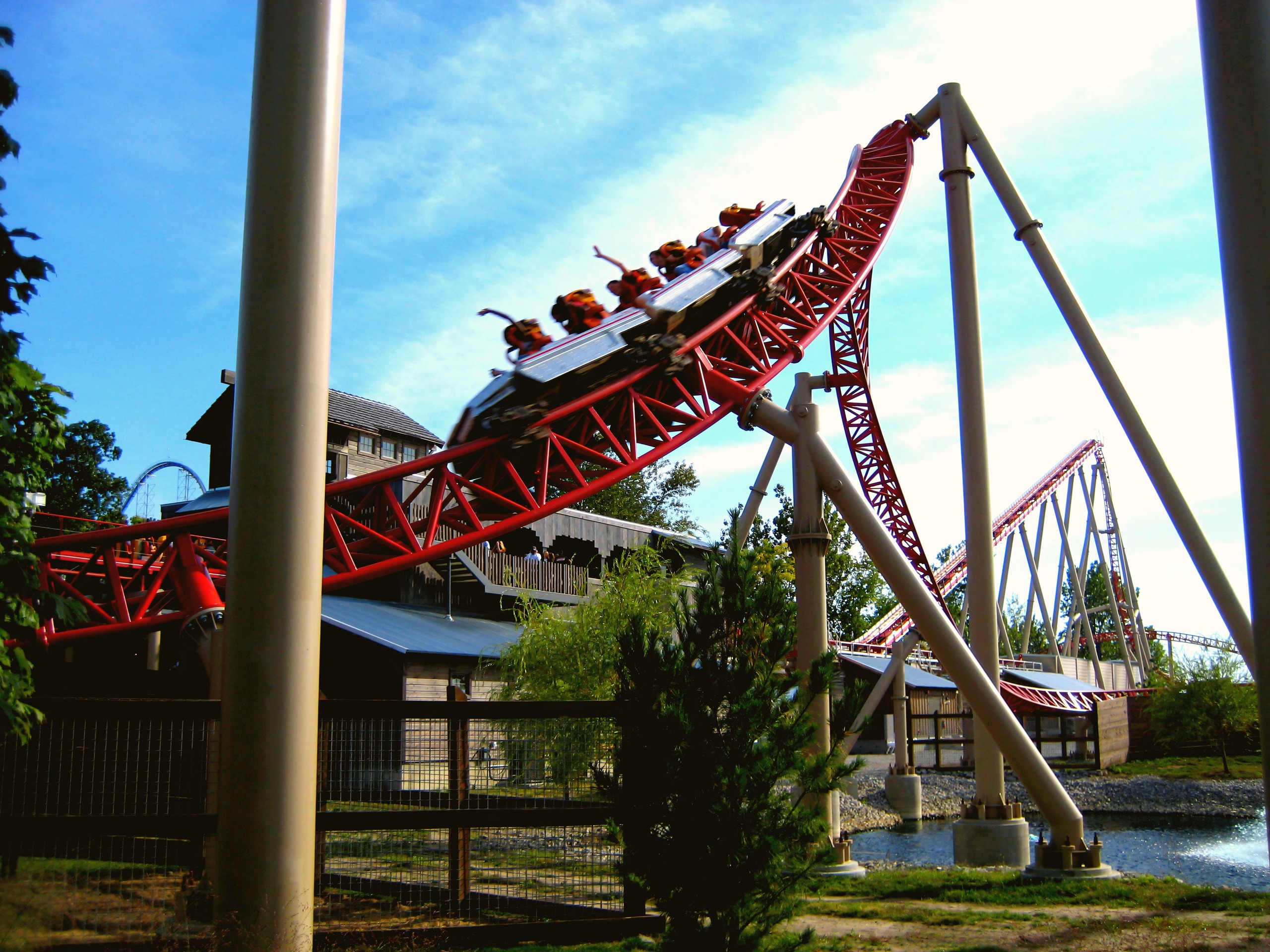 A Maverick train cresting a hill beside the station at Cedar Point, riders' hands up