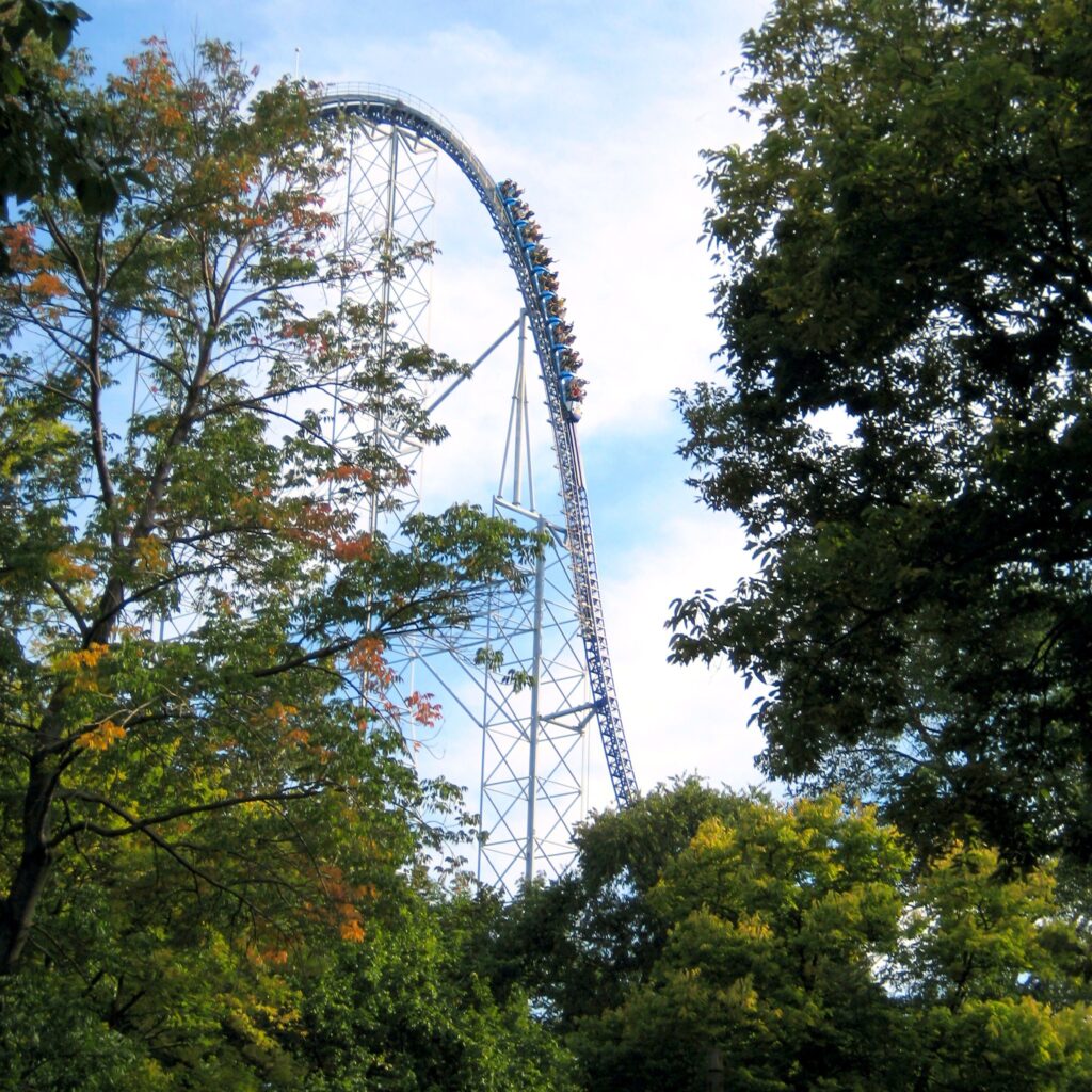 A Millennium Force train climbing the 310-foot lift hill, framed by early-fall trees at Cedar Point, September 2007