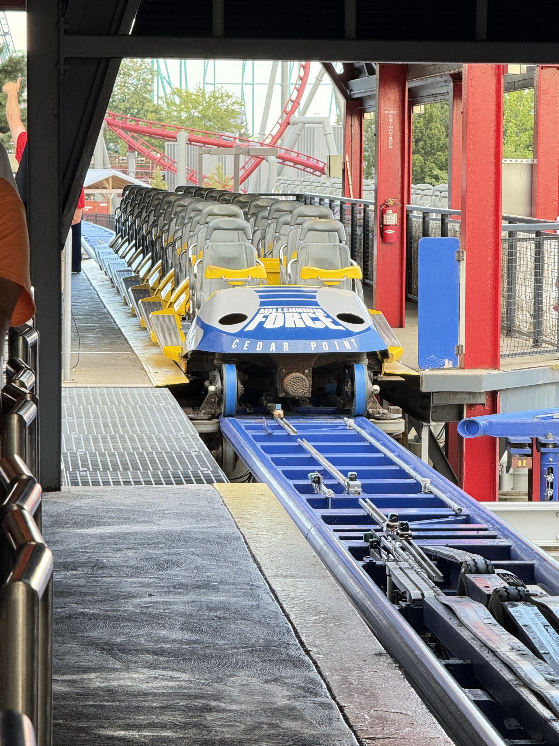 A Millennium Force train pulling into the station with red supports behind