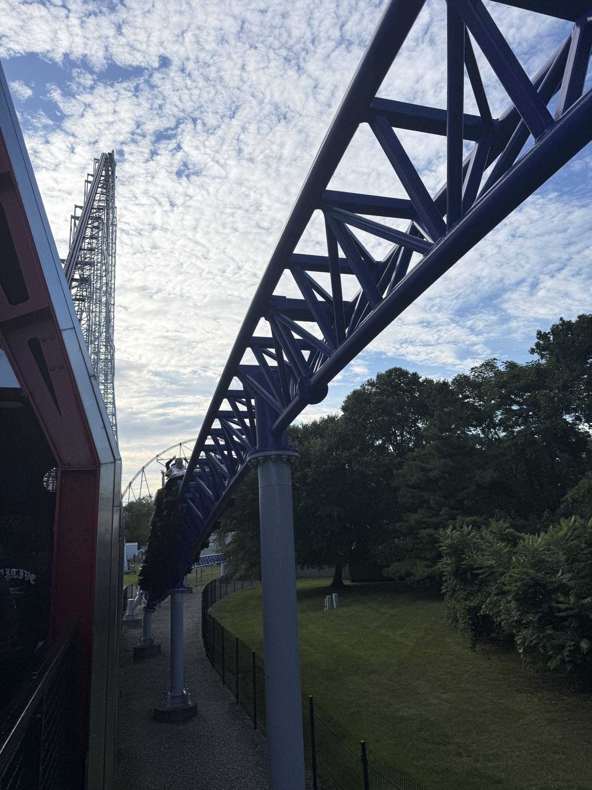 A Millennium Force train returning on the brake run beneath the blue track, lift hill behind
