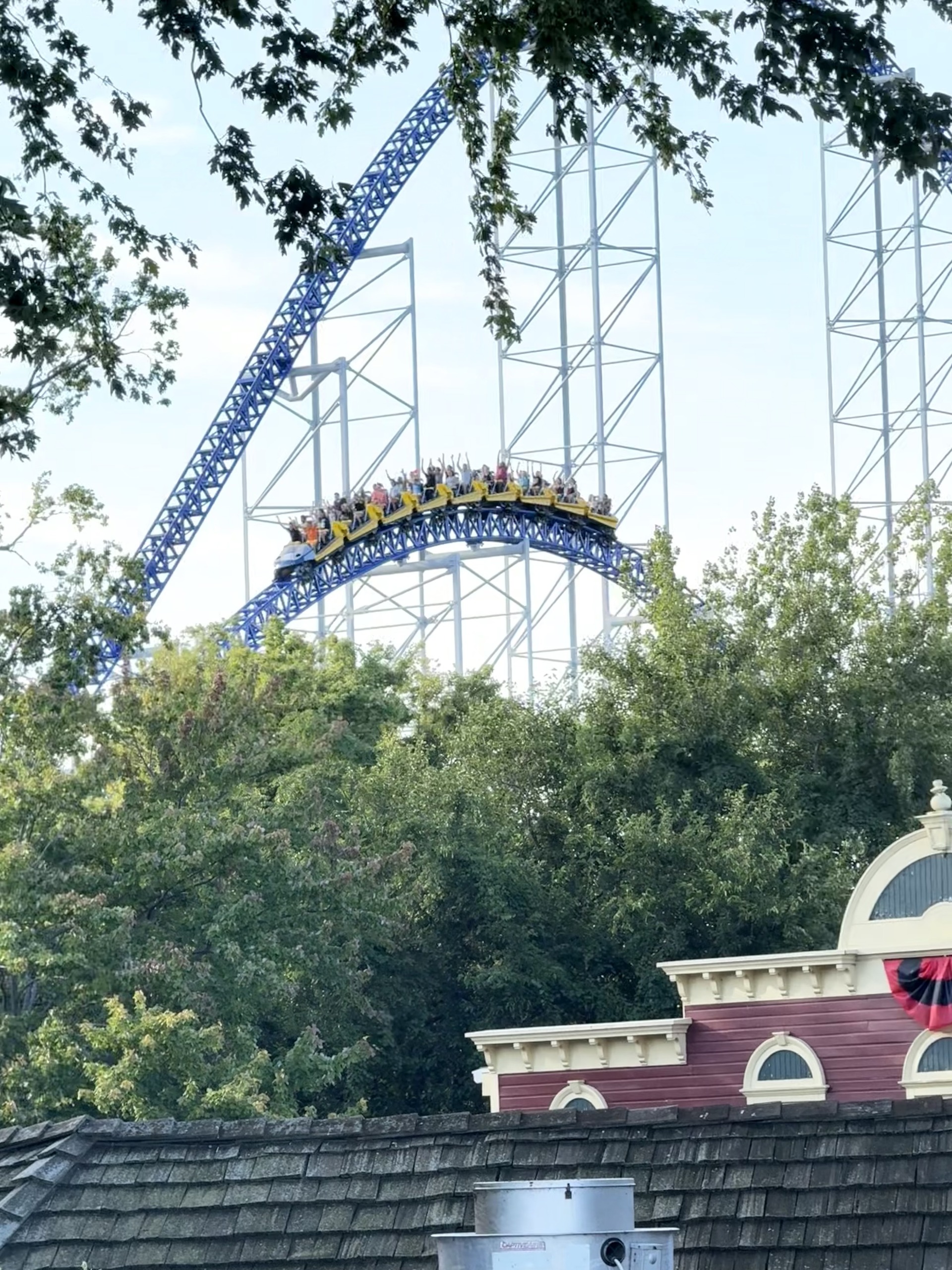 A Millennium Force train centered on the crest of the overbanked turn above the station rooftop