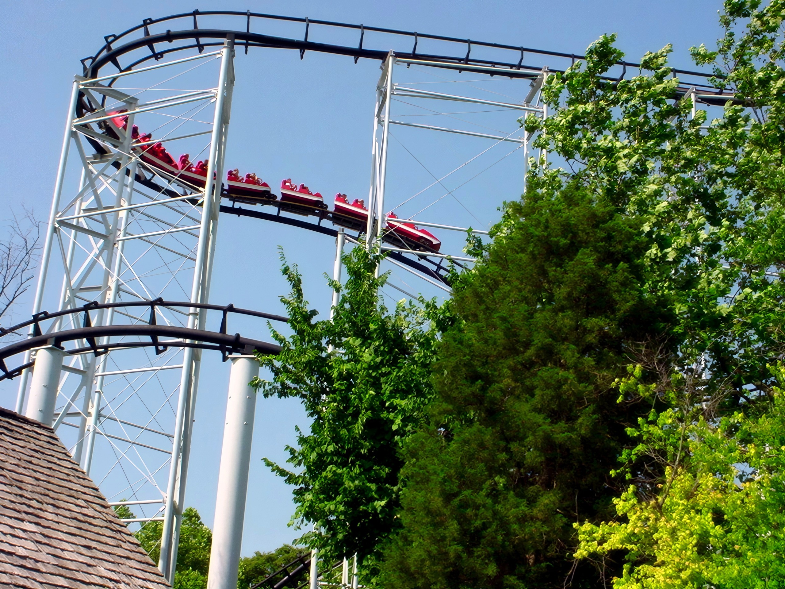 A red Ninja train on the track above the trees at Mid America Adventure, June 2002