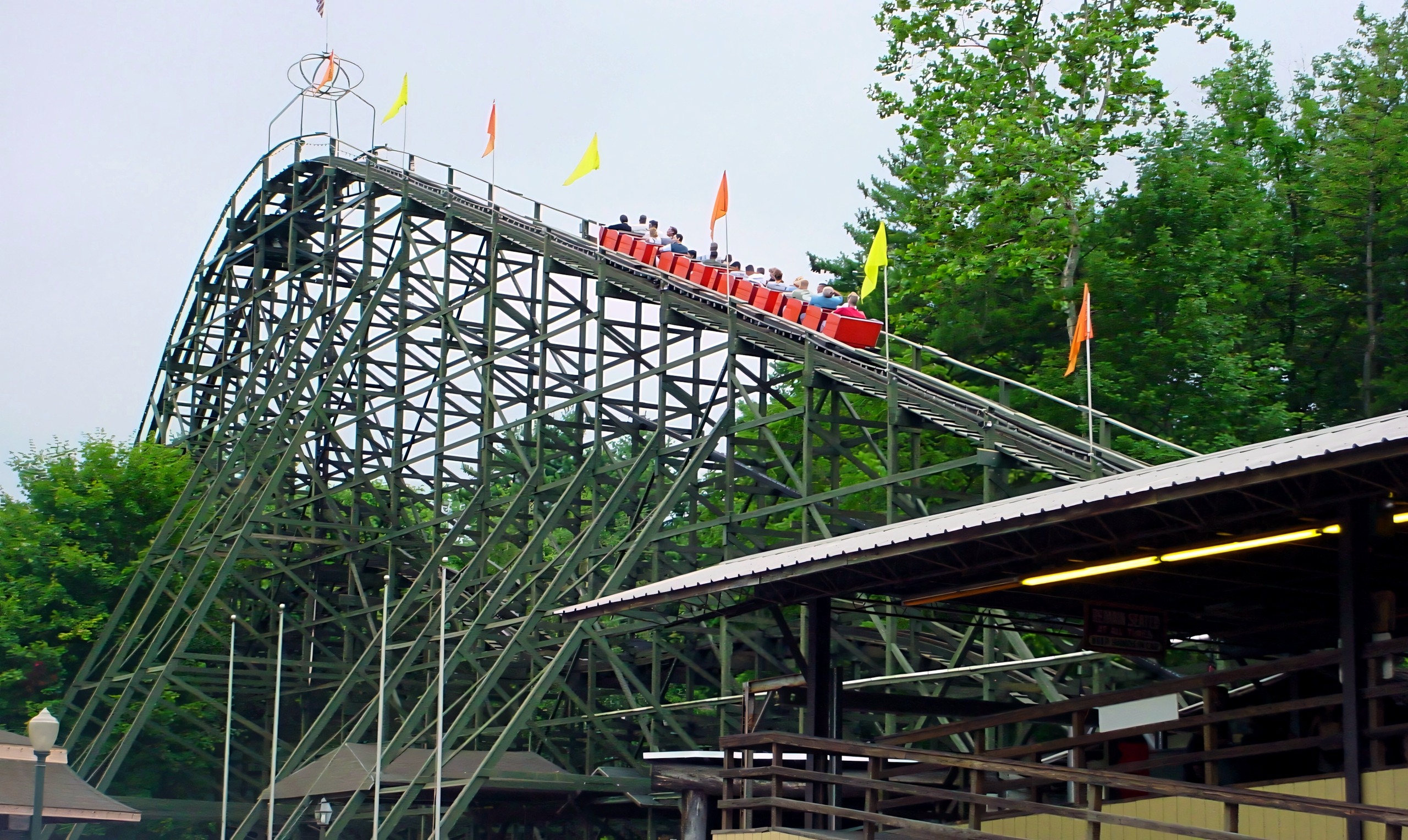 A red Phoenix train climbing the flag-lined lift hill above the station, July 2003