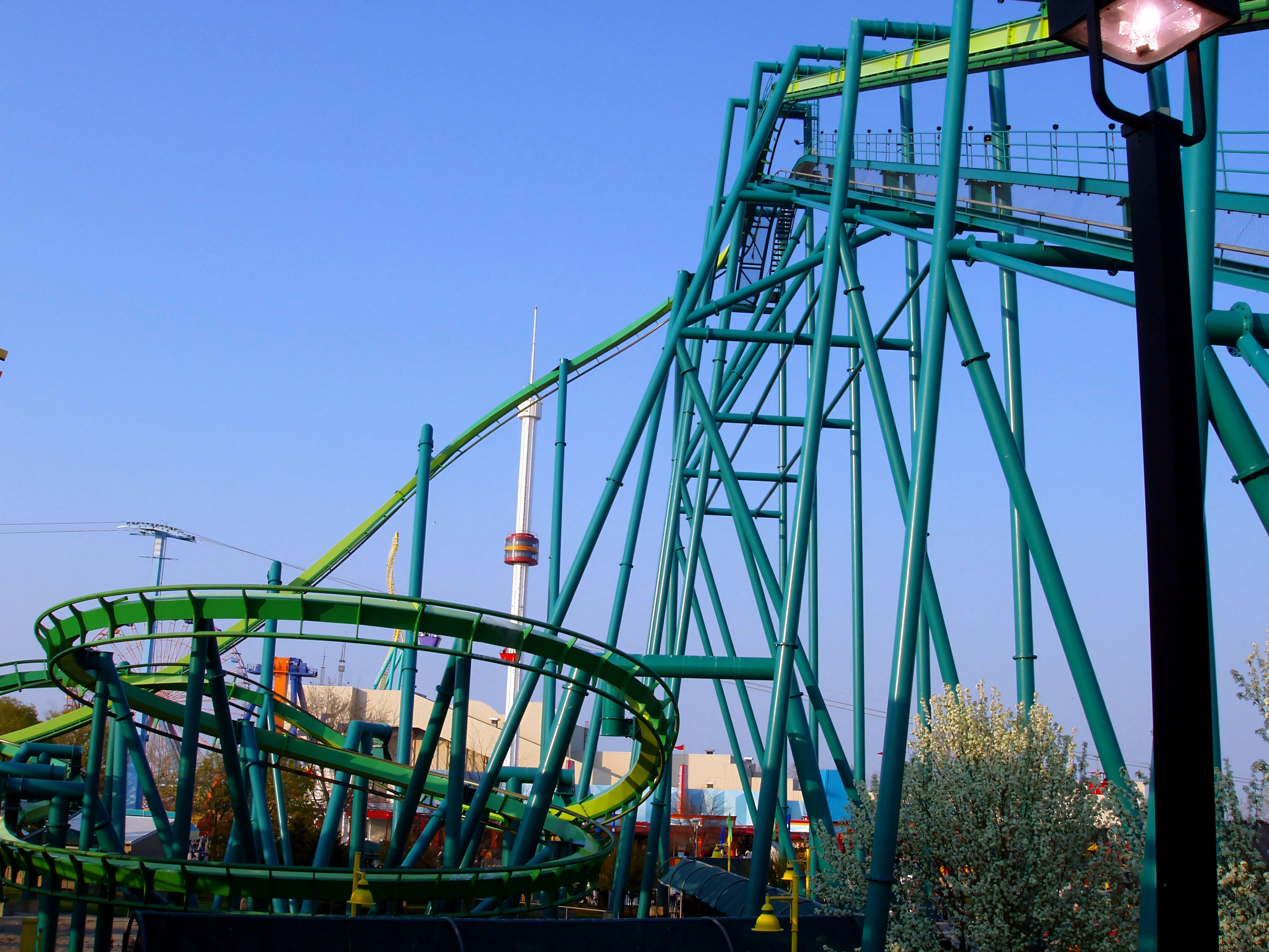 Corkscrew's teal double-loop track against blue sky, tower ride behind, Raptor, May 2005