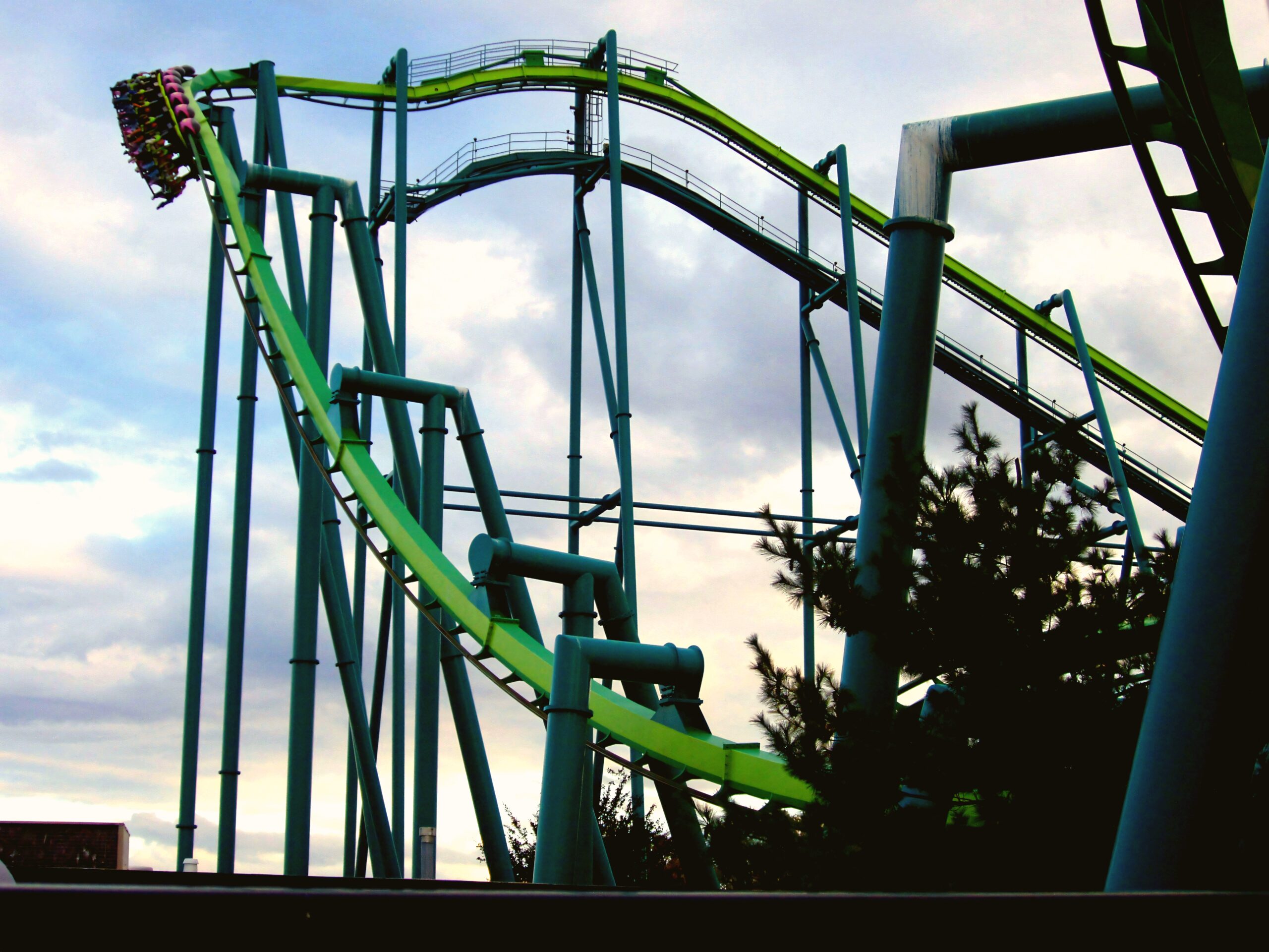 A Raptor train coming down the drop at dusk at Cedar Point, riders' legs dangling