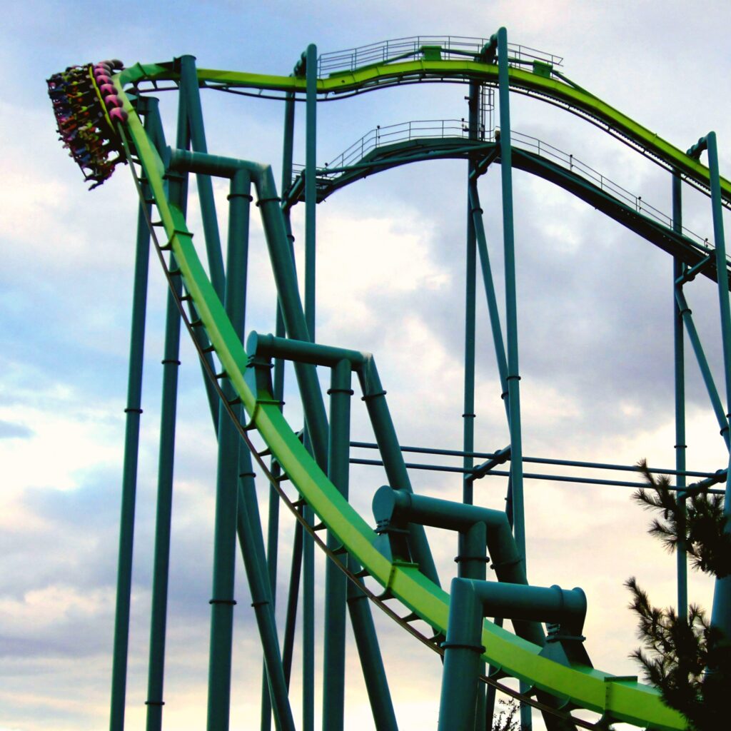 A Raptor train coming down the drop at dusk at Cedar Point, riders' legs dangling