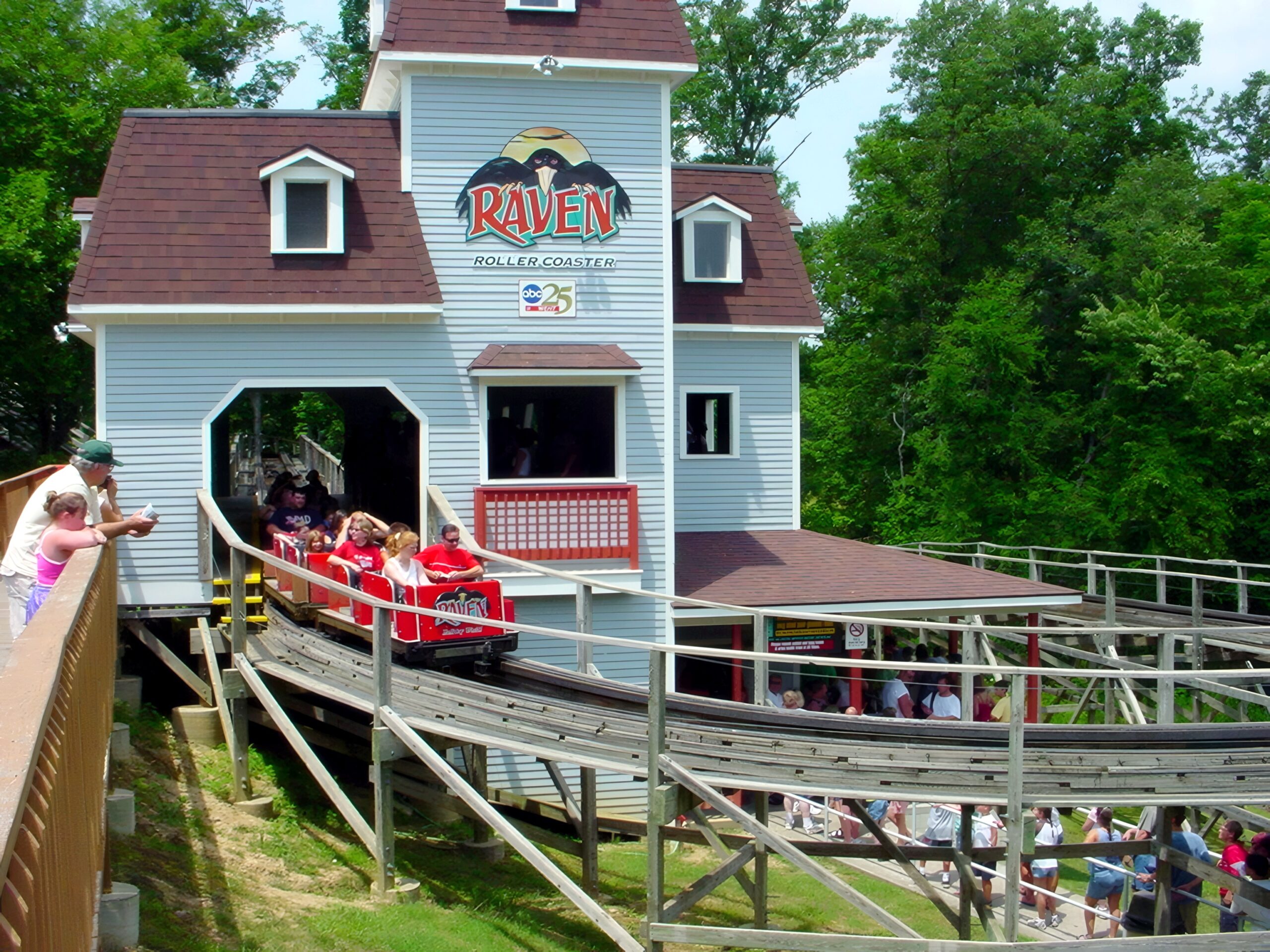 A Raven train arriving at the station house, riders waving, July 2002
