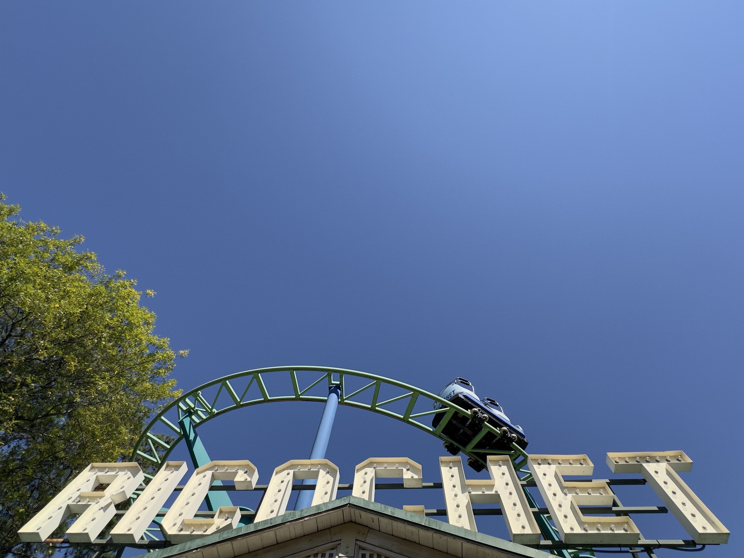 A Ricochet car on the hairpin above the marquee letters, Carowinds, October 2024