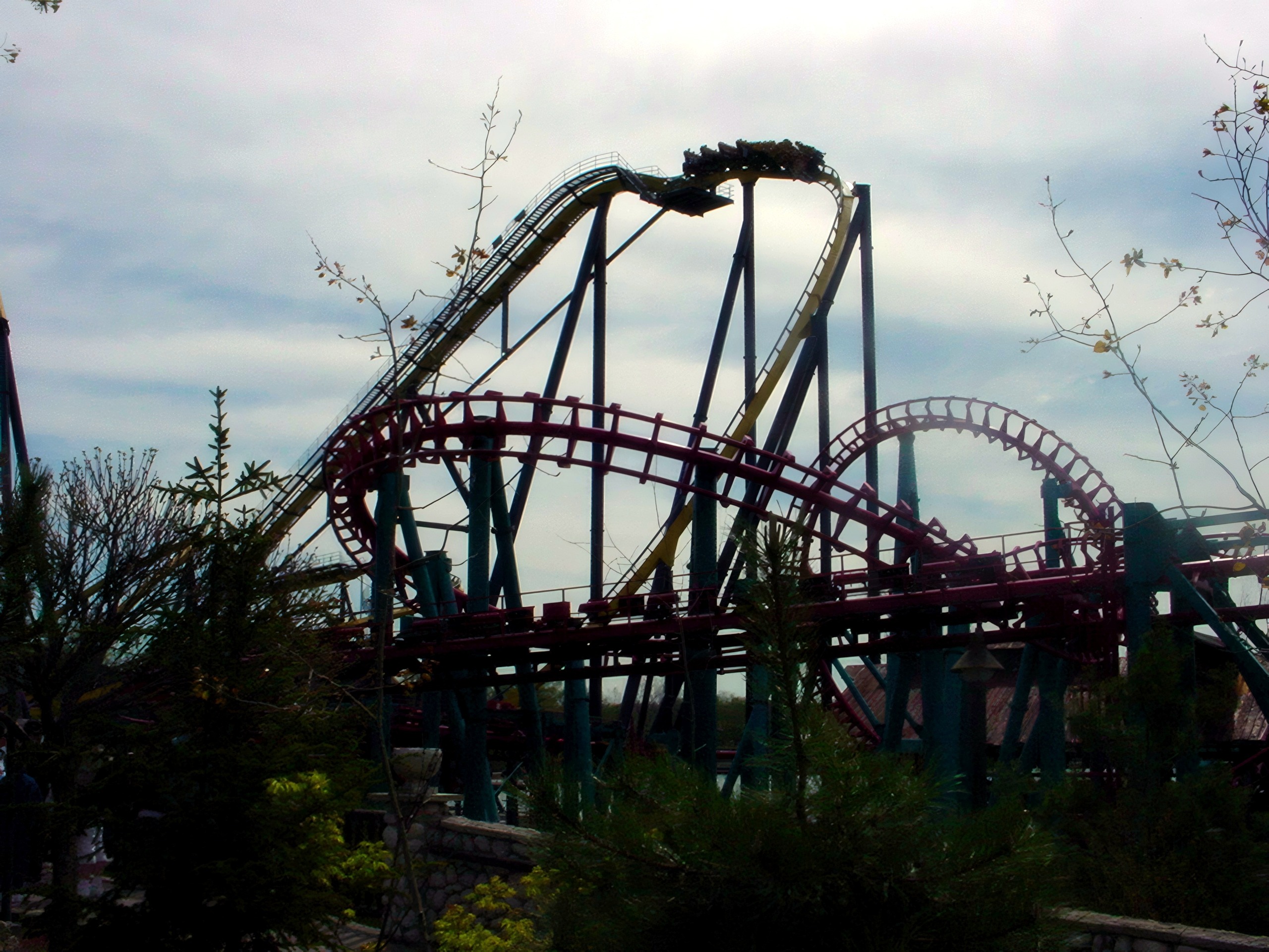 Close view of teal-maroon coaster train cresting hill among trees, Serial Thriller, May 2002