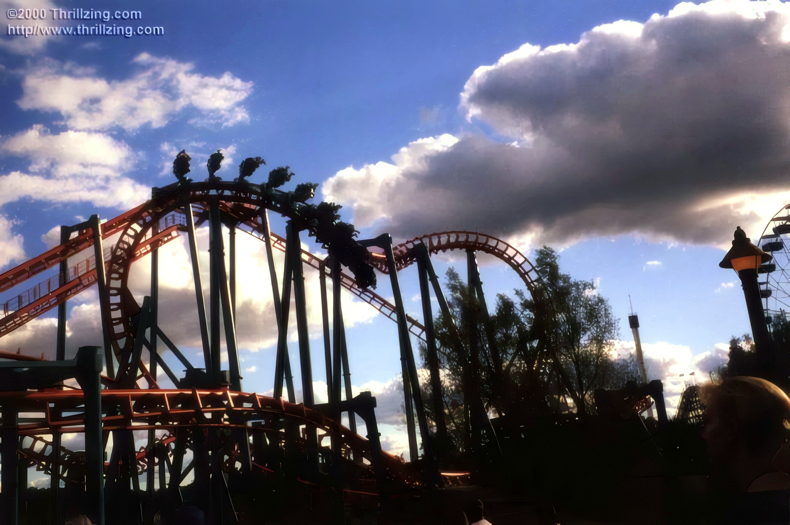 Coaster train cresting hill, dramatic clouds behind, Serial Thriller, May 2000