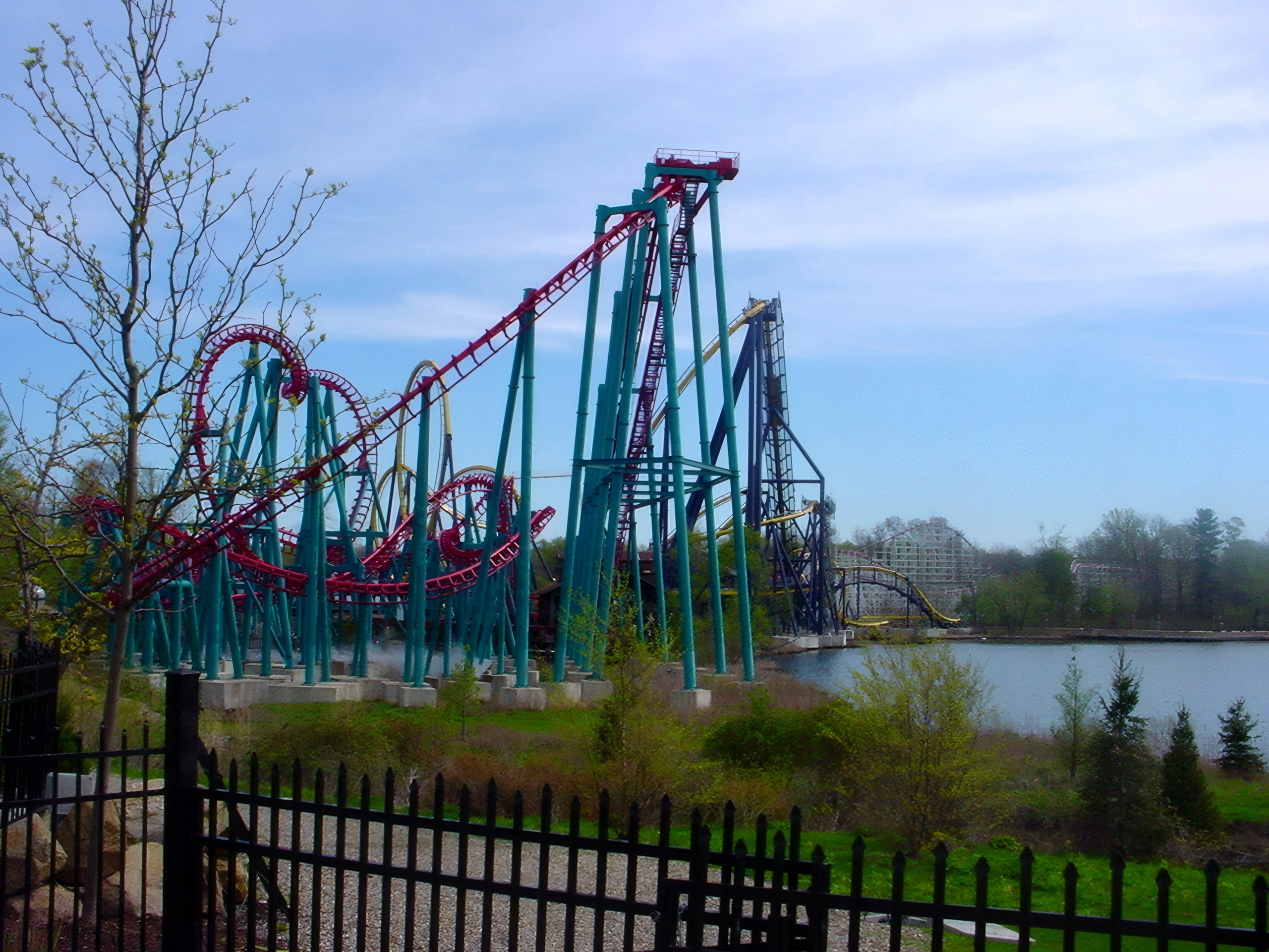 Teal-and-maroon looping coaster beside lake, another coaster visible distant, Serial Thriller, May 2002