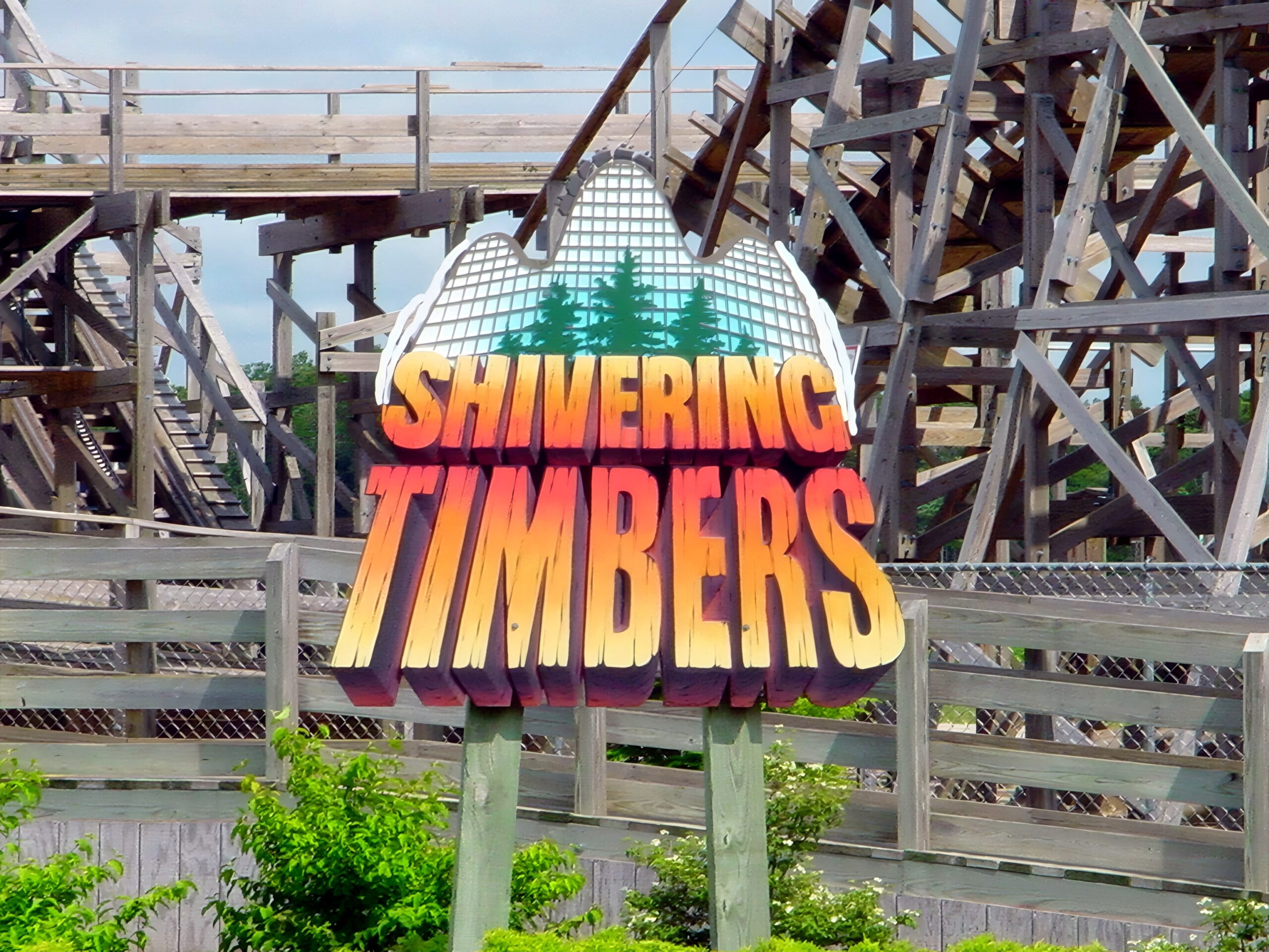 Shivering Timbers entrance sign with the wooden structure and lift hill behind it, June 2002