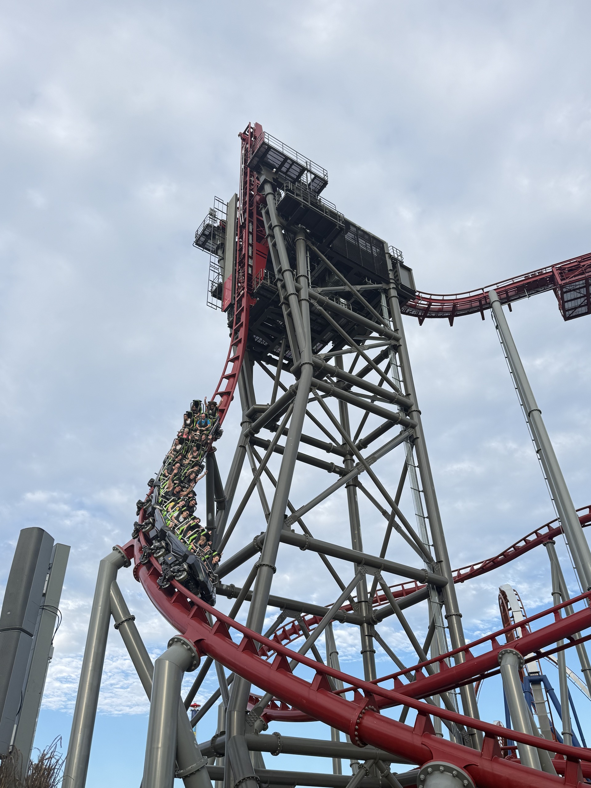 The Siren's Curse tilt tower with a train on the red track below, low angle