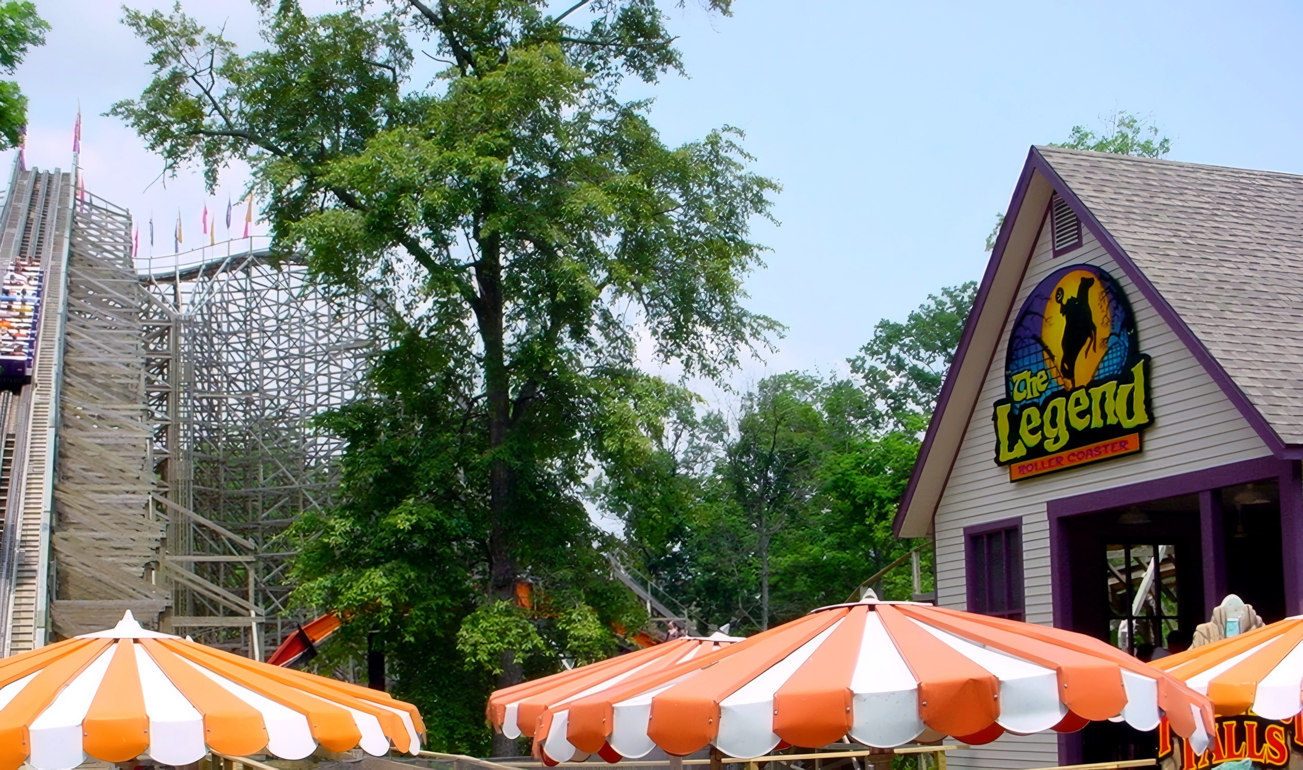 The Legend's queue house and sign with the lift hill behind the trees, July 2002