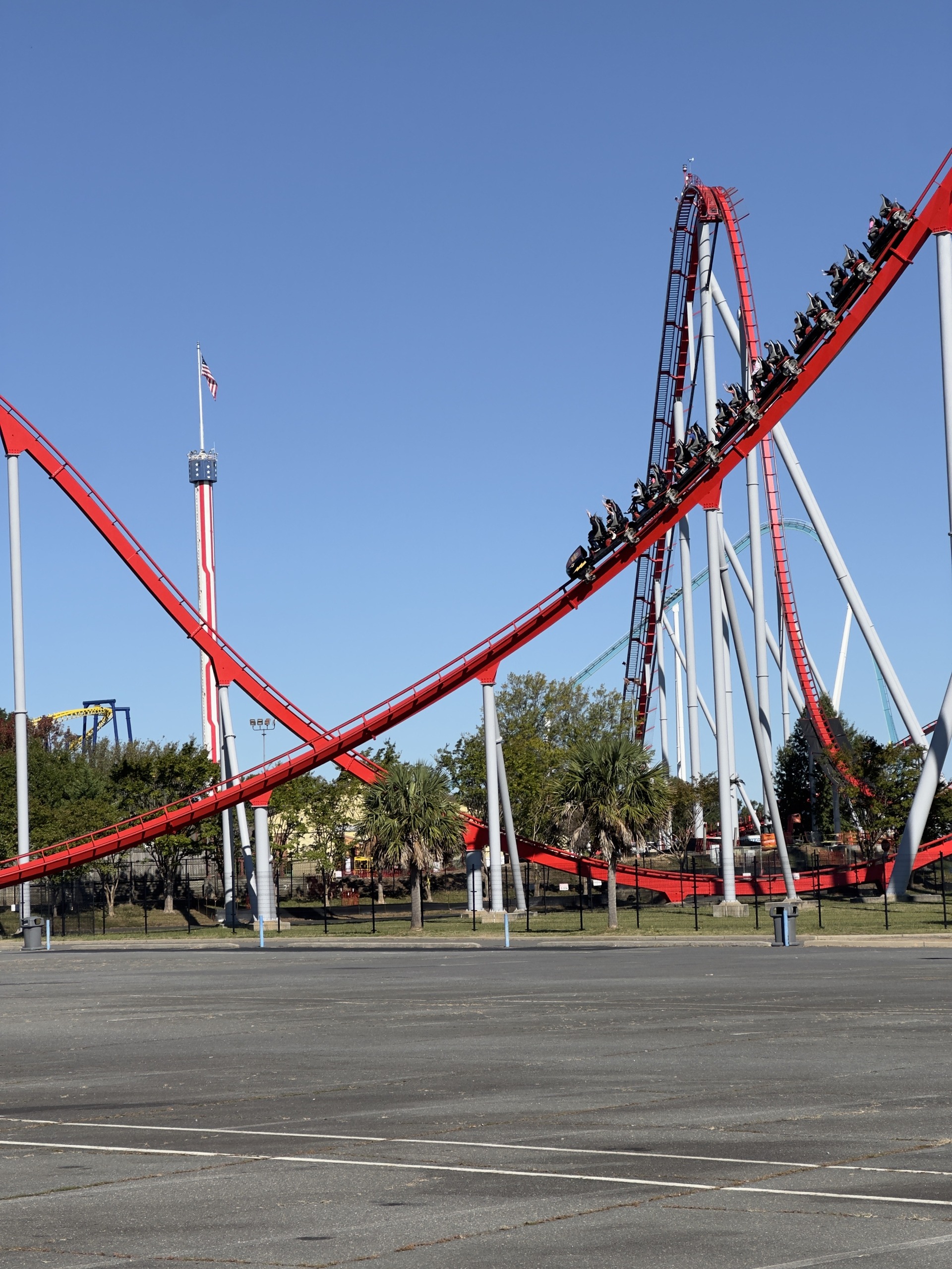 A Thunder Striker train heading into the hills with the observation tower behind, Carowinds, October 2024