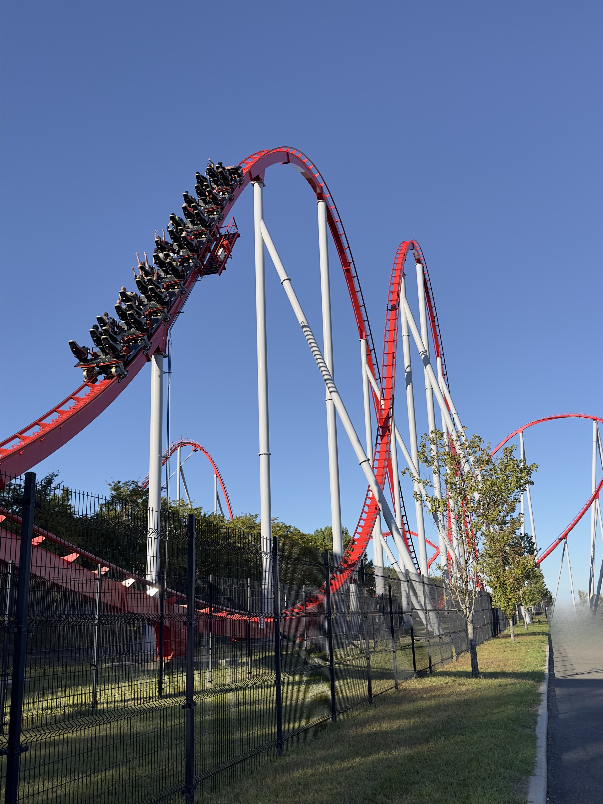 A Thunder Striker train climbing the red hill with more hills beyond, Carowinds, October 2024