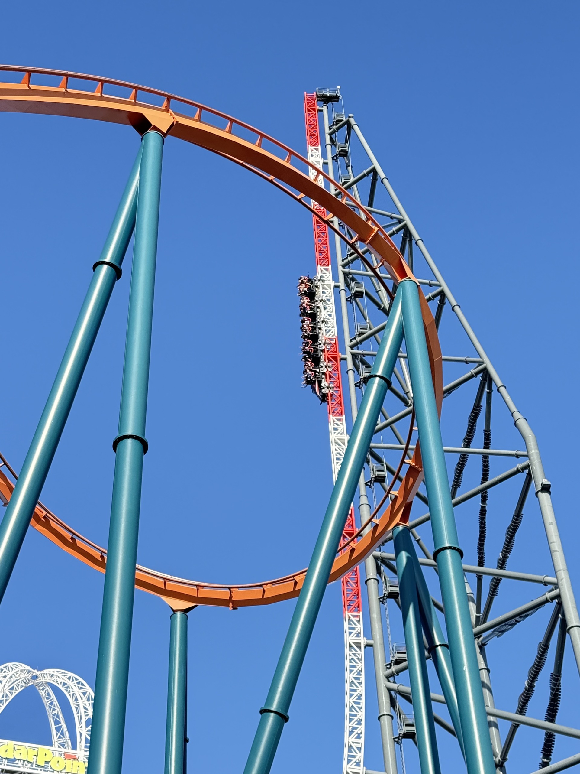 Top Thrill 2's spike with a train climbing, seen through Rougarou's orange track and green supports