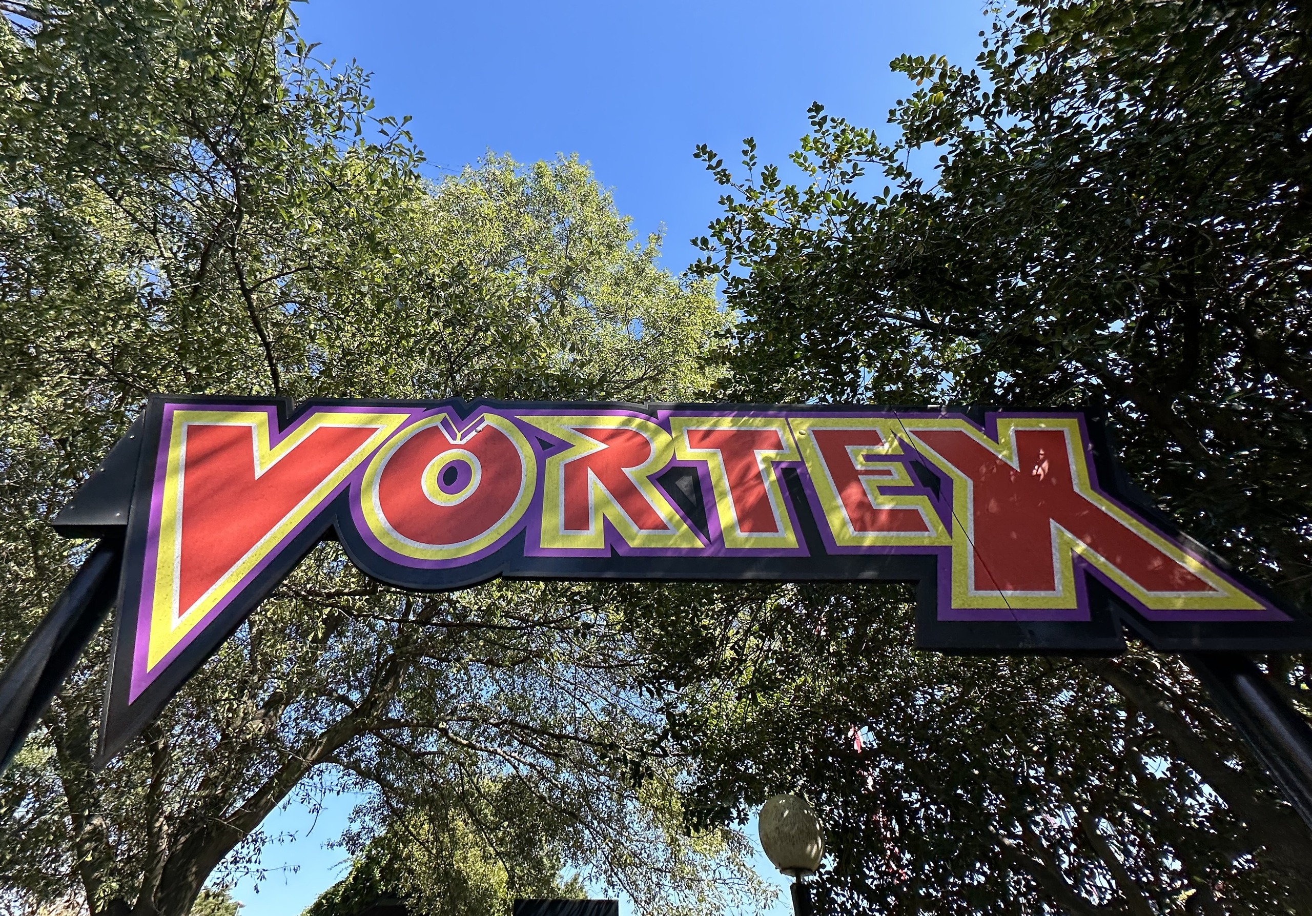 The red and purple Vortex entrance sign under the trees, Carowinds, October 2024