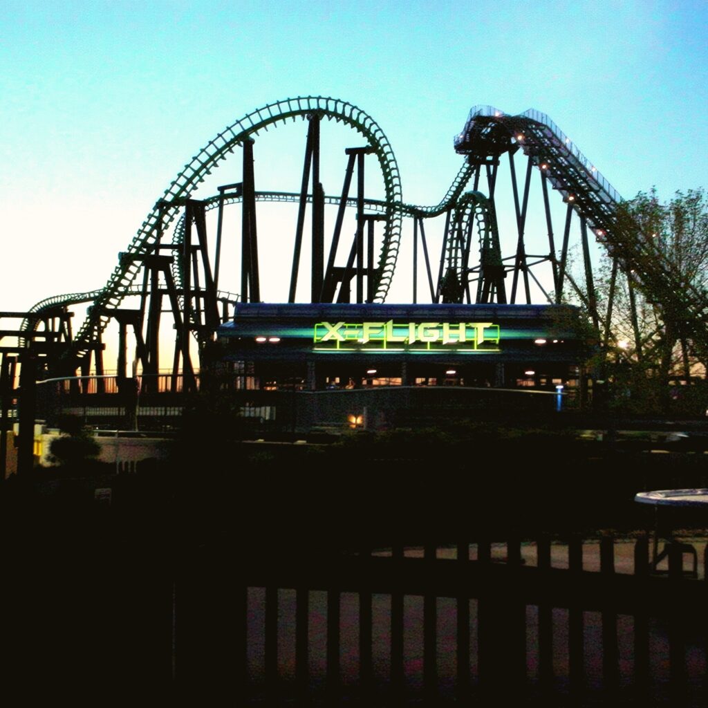 X-Flight silhouetted against the twilight sky with its station sign lit, Six Flags Worlds of Adventure, May 2002