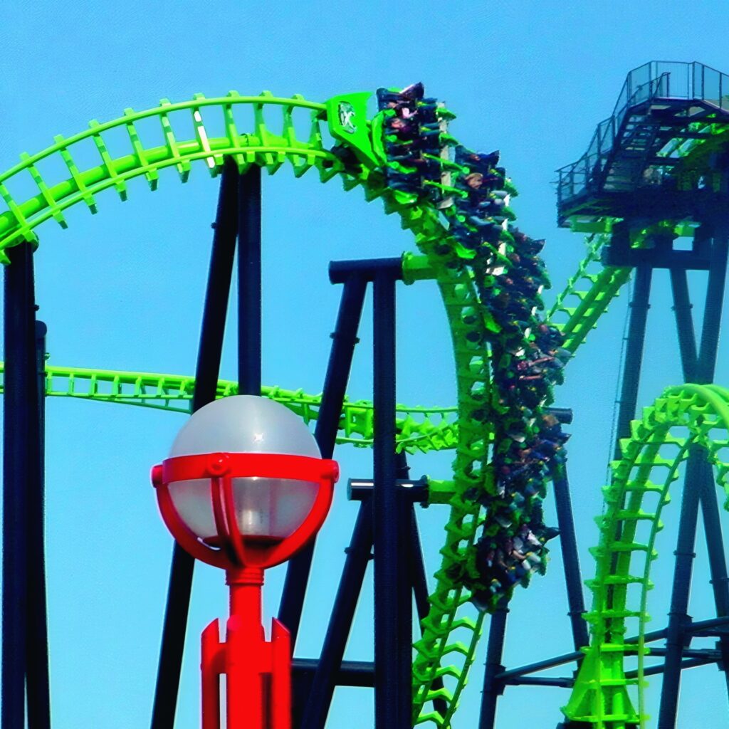 X-Flight train riding the top of a lime-green inversion at Six Flags Worlds of Adventure, May 2002