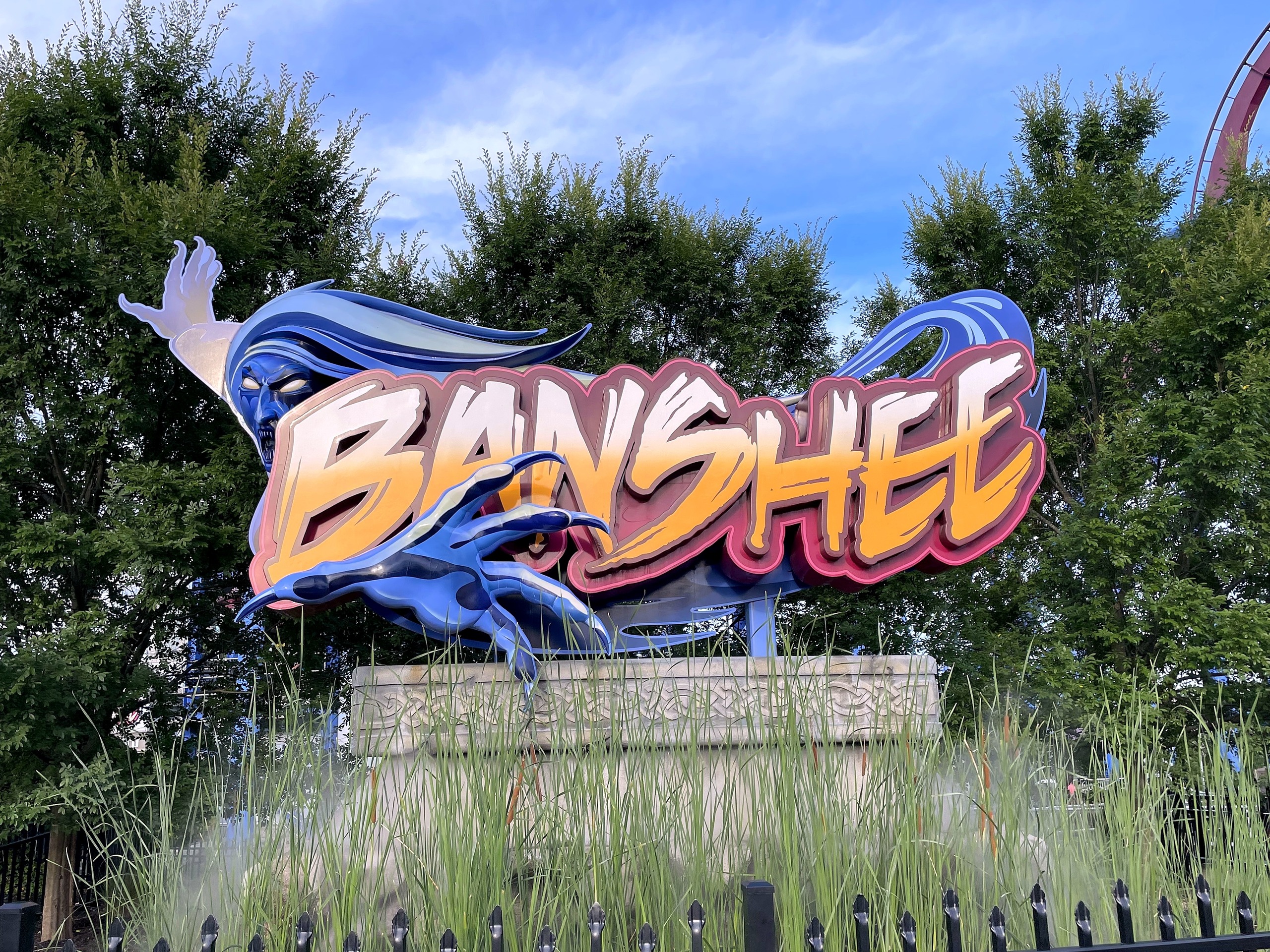 The Banshee sign with its screaming blue spirit above the tall grass at the entrance, Kings Island, July 2022