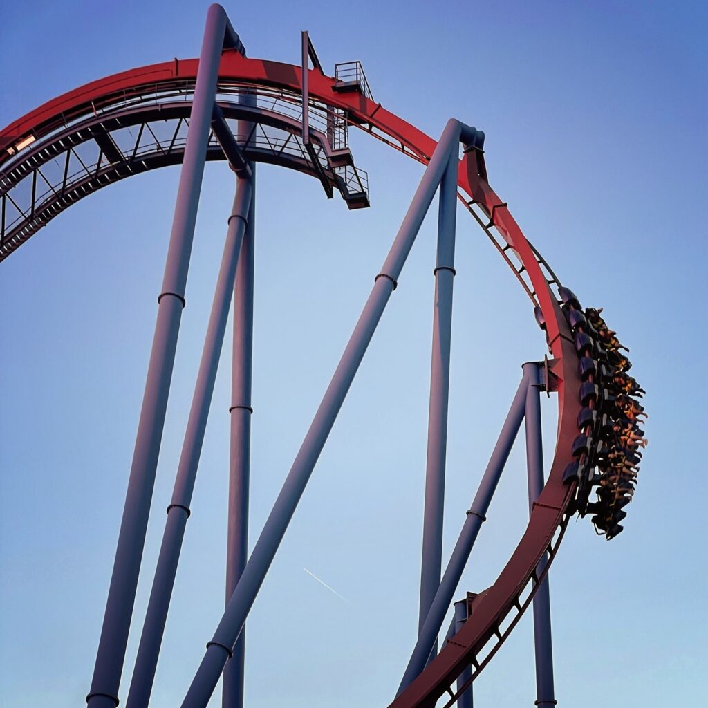 A Banshee train with riders' legs dangling on the outside of the maroon curve, Kings Island, July 2022