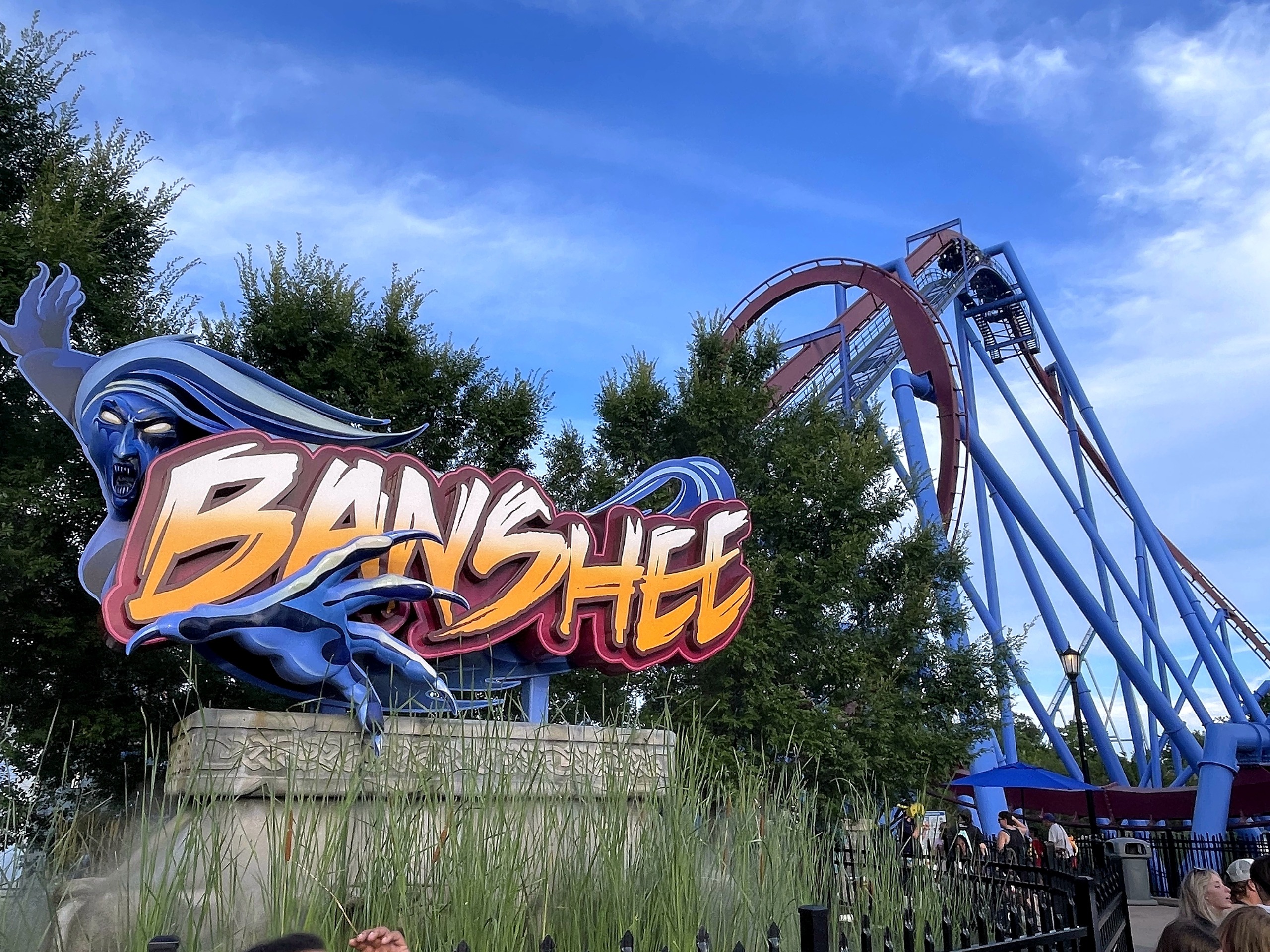 The Banshee sign with the maroon track and blue supports of the vertical loop behind it, Kings Island, July 2022