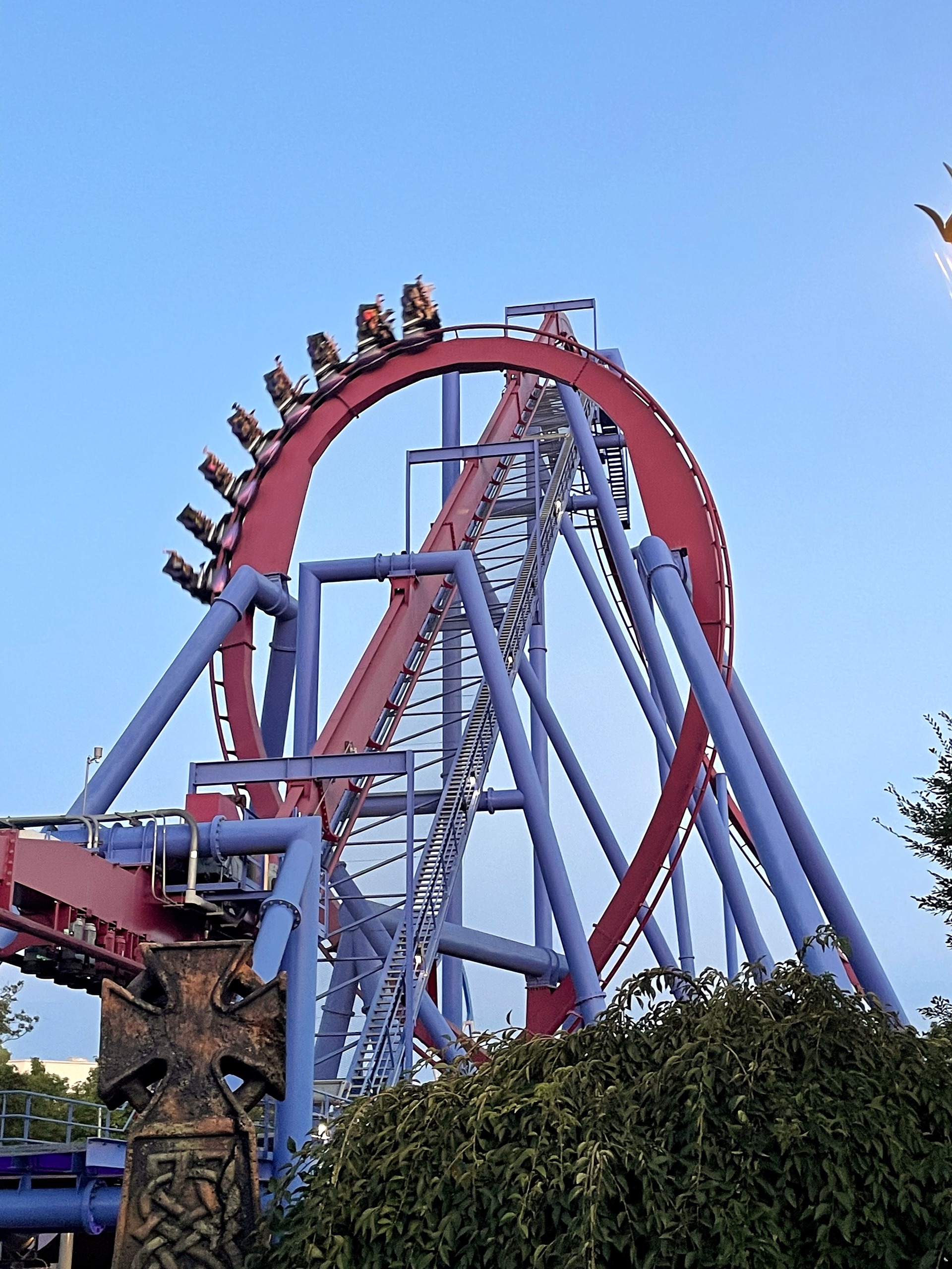 A Banshee train at the top of the loop above a carved stone cross in the plaza, Kings Island, July 2022