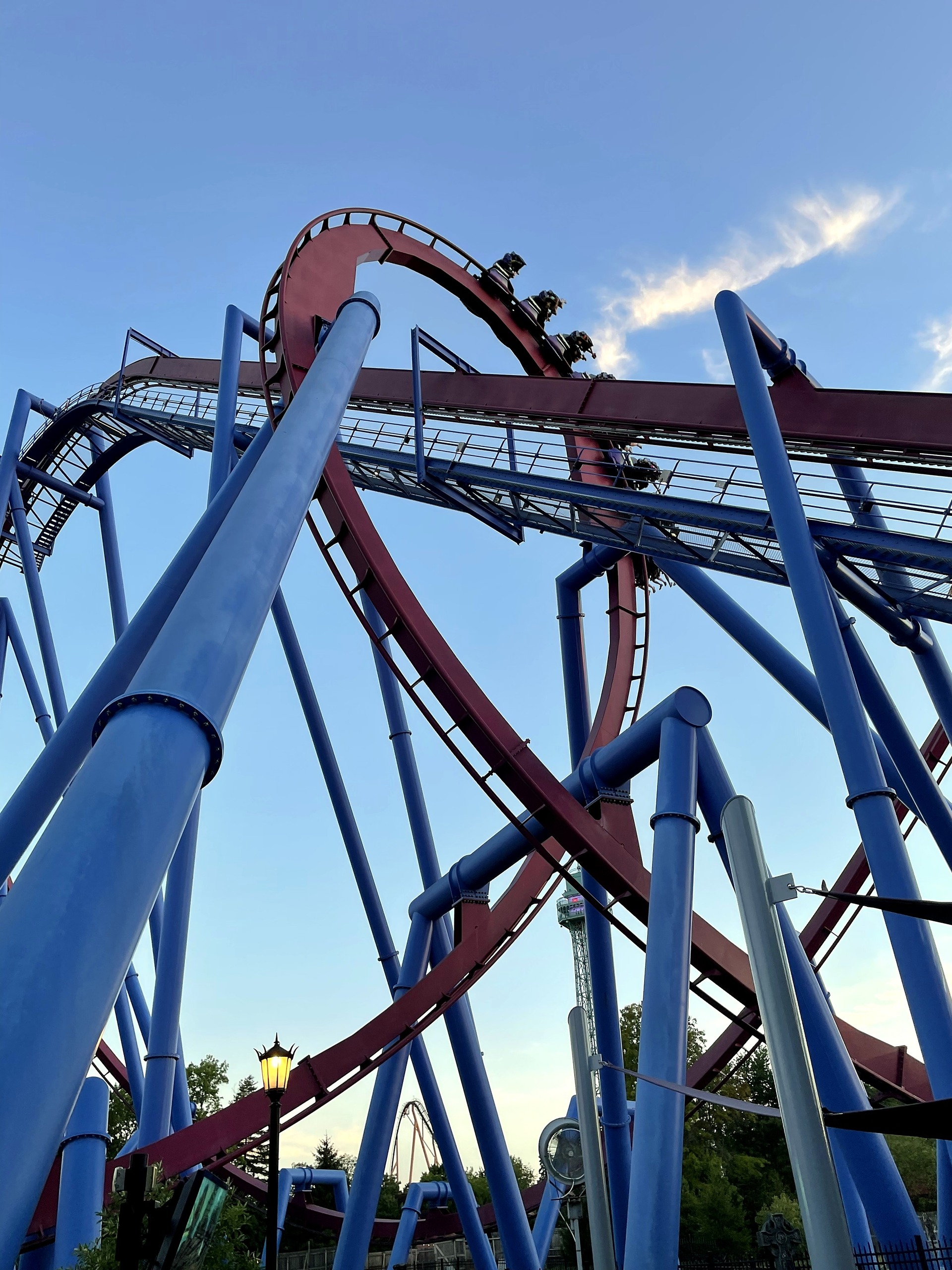 A Banshee train in the vertical loop above the midway lamp posts, Kings Island, July 2022