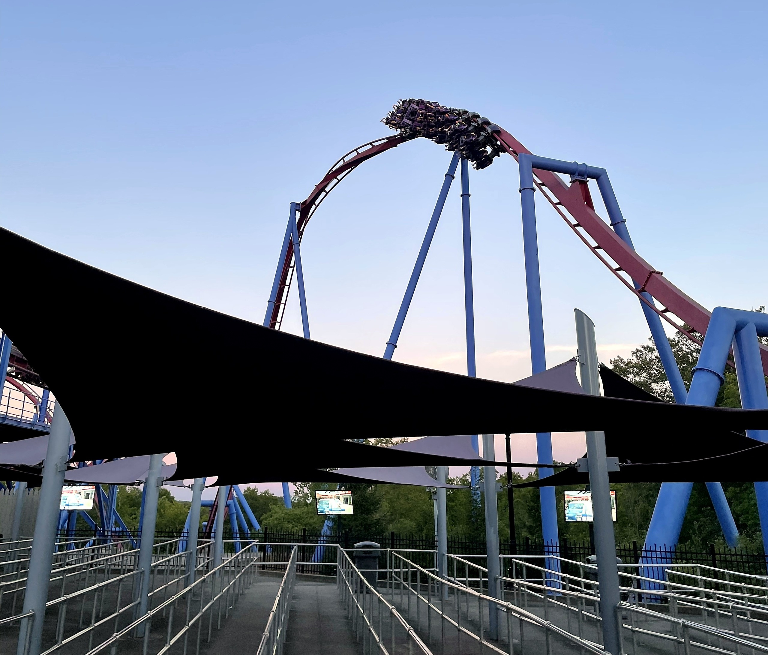 A Banshee train at the top of the track above the queue's black shade sails, Kings Island, July 2022