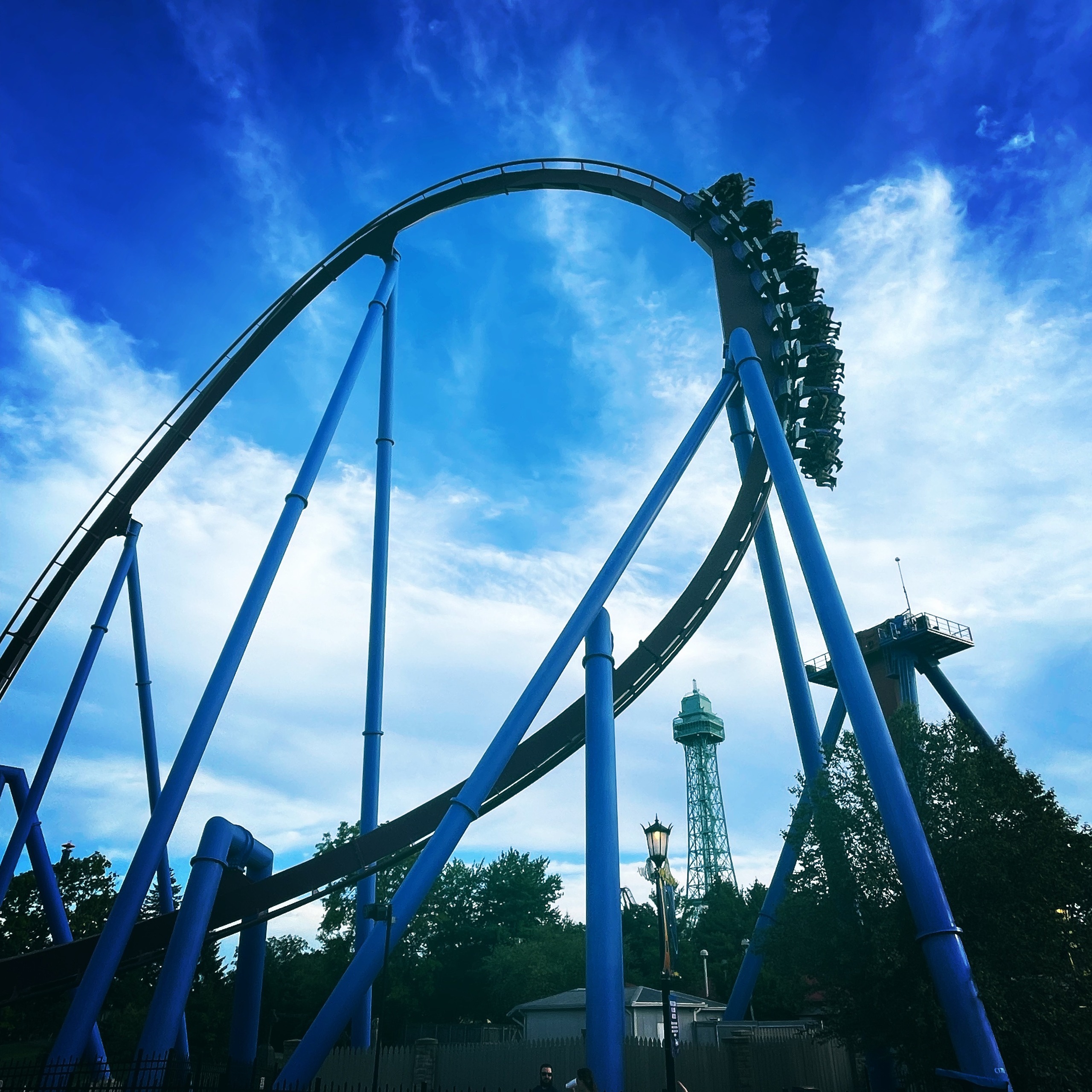 A Banshee train cresting the top of the track above the blue supports with the Eiffel Tower behind, Kings Island, July 2022