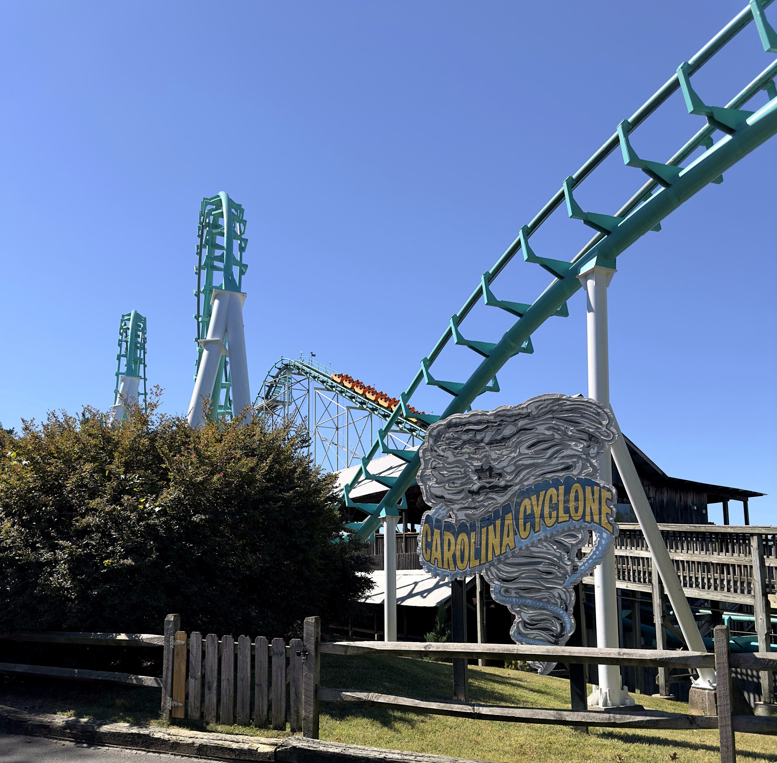 The Carolina Cyclone tornado sign in front of the teal track, loops and wooden station building at Carowinds, October 2024
