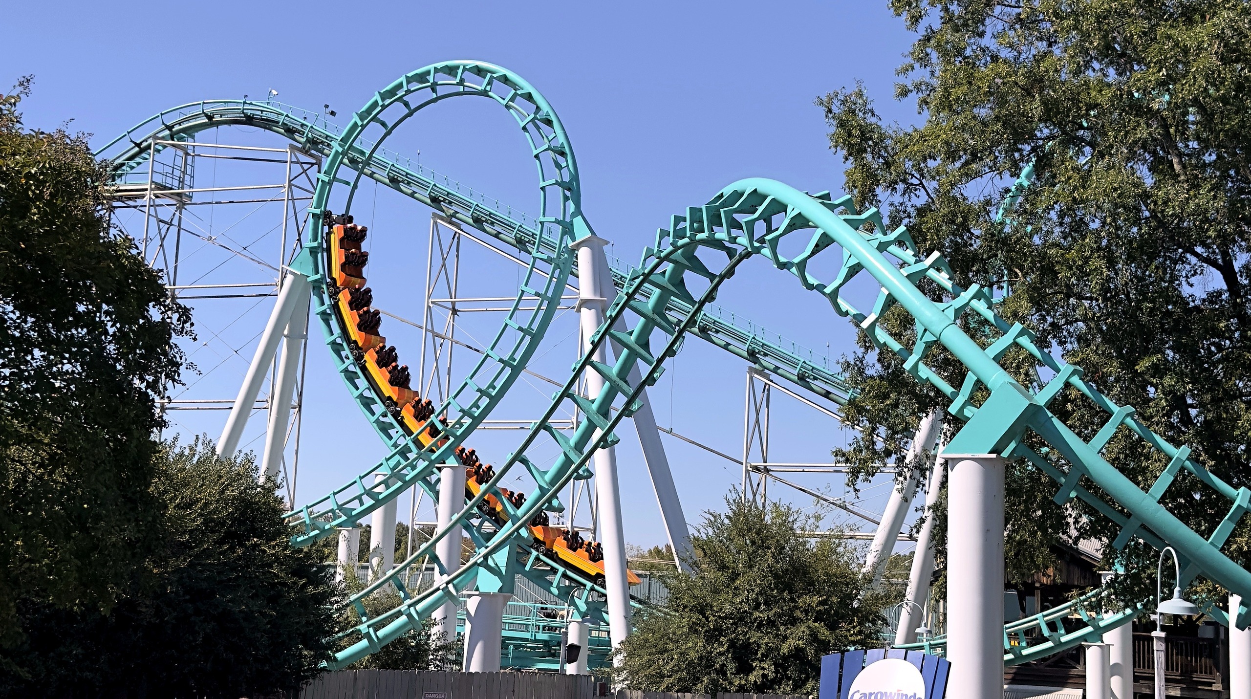 An orange Carolina Cyclone train diving down the vertical loop at Carowinds, October 2024