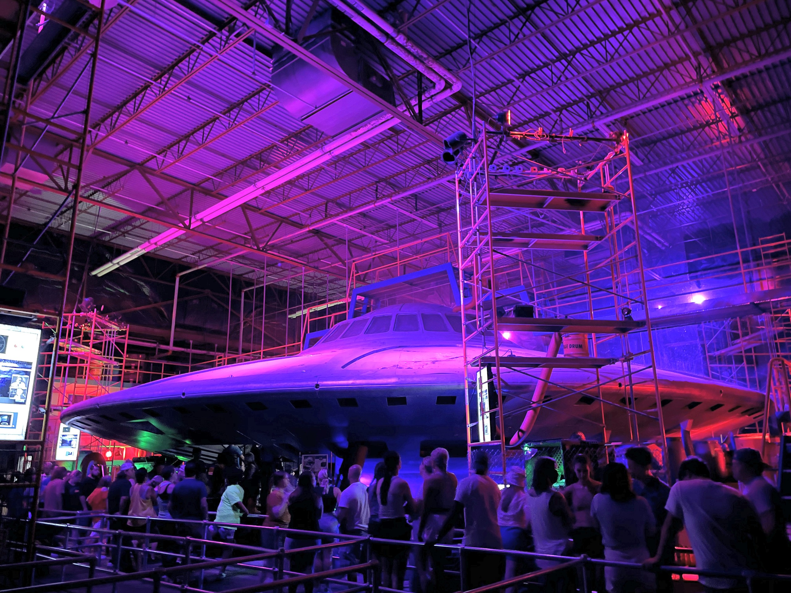 The flying saucer inside Flight of Fear's darkened hangar queue, lit purple, Kings Island, July 2022