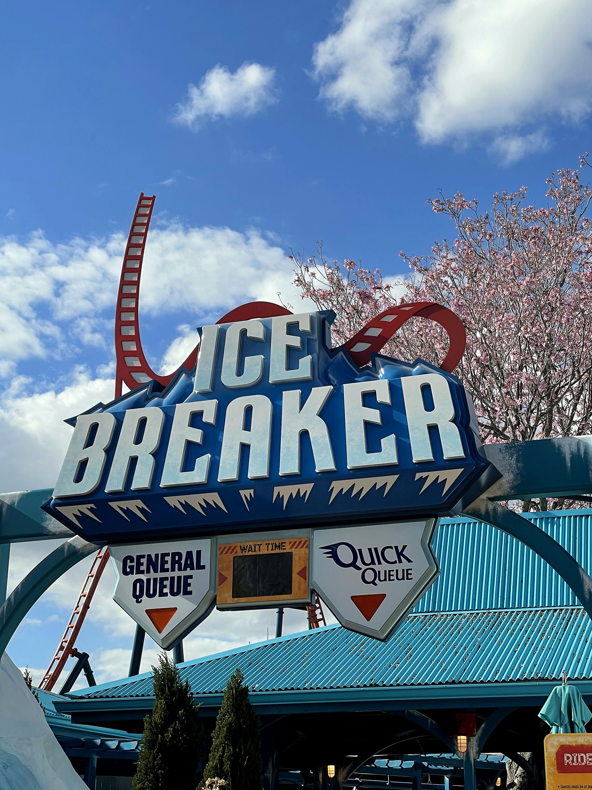 The Ice Breaker entrance sign with General Queue and Quick Queue signs and the orange track behind at SeaWorld Orlando, March 2021