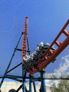 An Ice Breaker train climbing the orange spike, seen through the safety netting at SeaWorld Orlando, March 2021