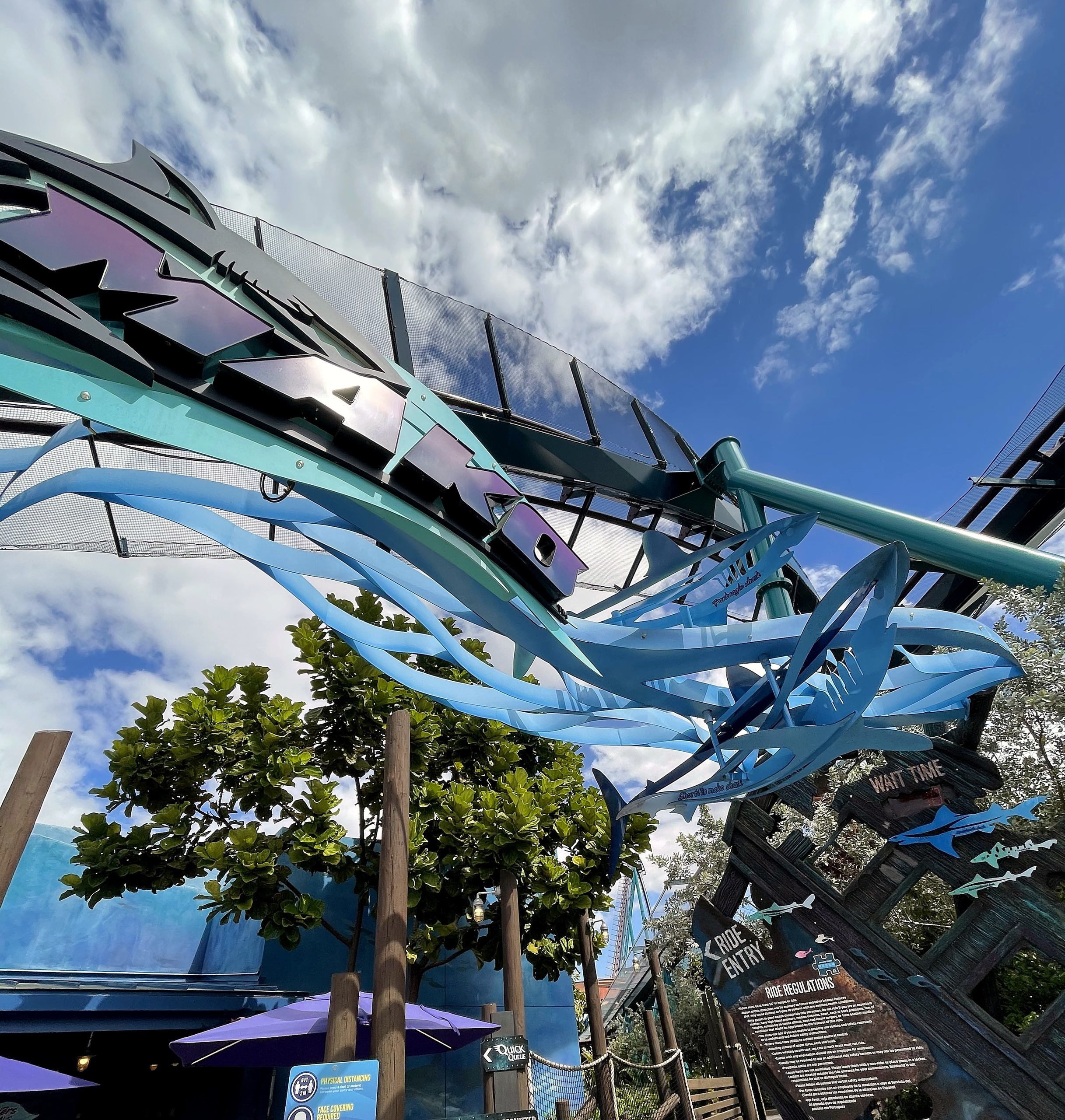 The Mako sign and shark sculptures above the queue entrance and the Ride Regulations board at SeaWorld Orlando, March 2021